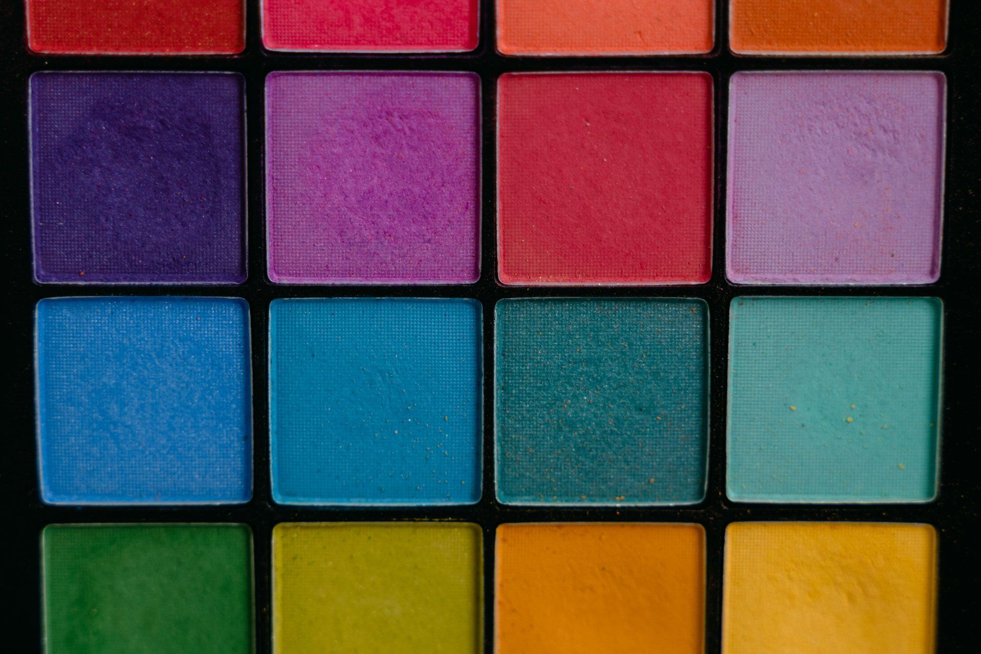 A close up of a colorful eyeshadow palette on a black background.