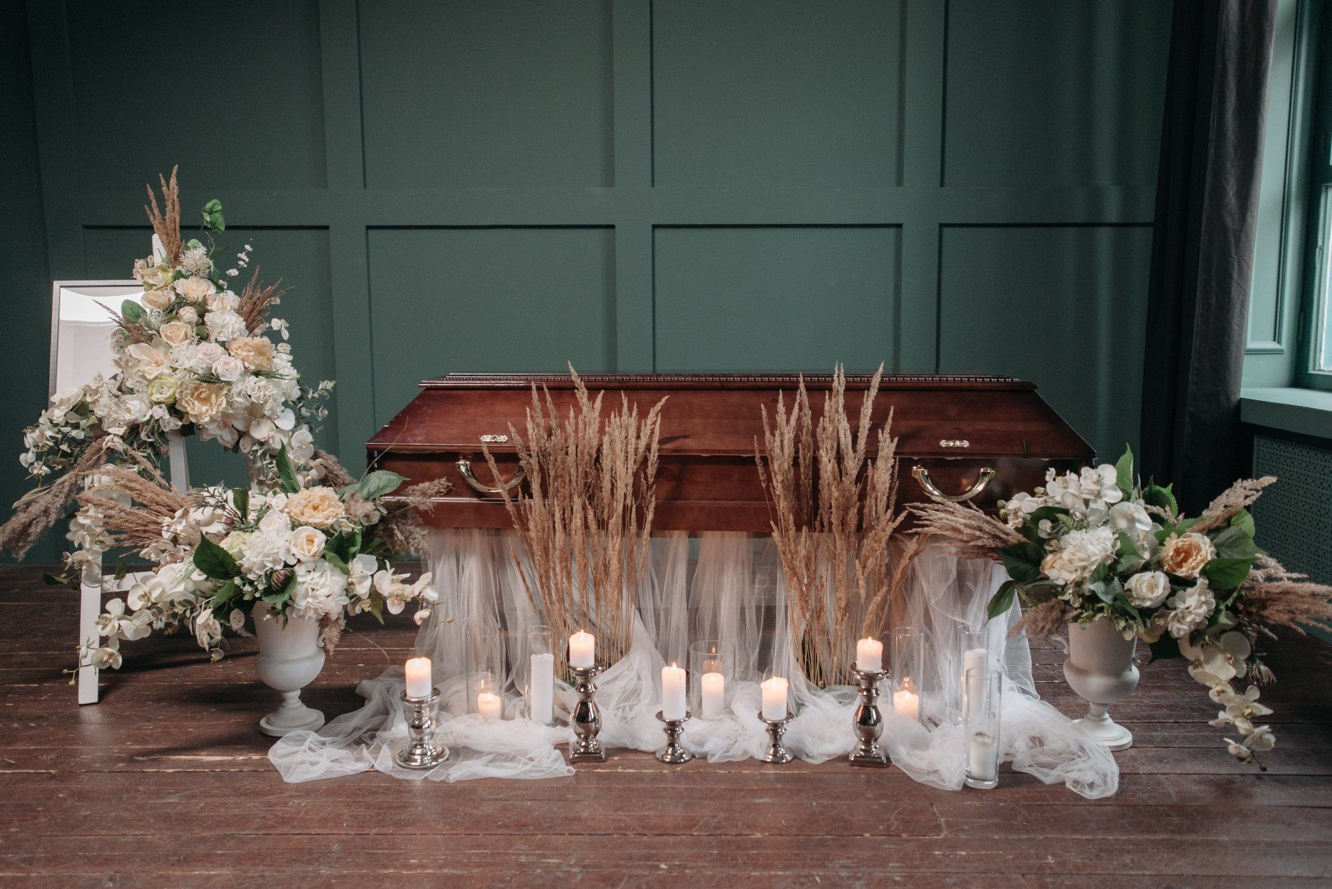 A casket at a funeral with flowers and candles around it.
