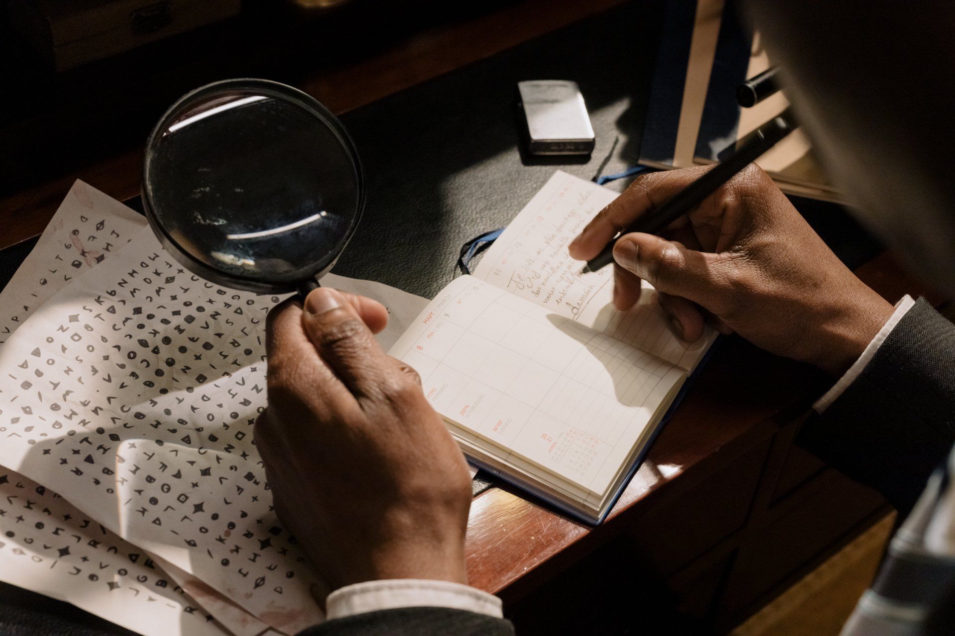 un uomo tiene in mano una lente d' ingrandimento mentre scrive su un taccuino .