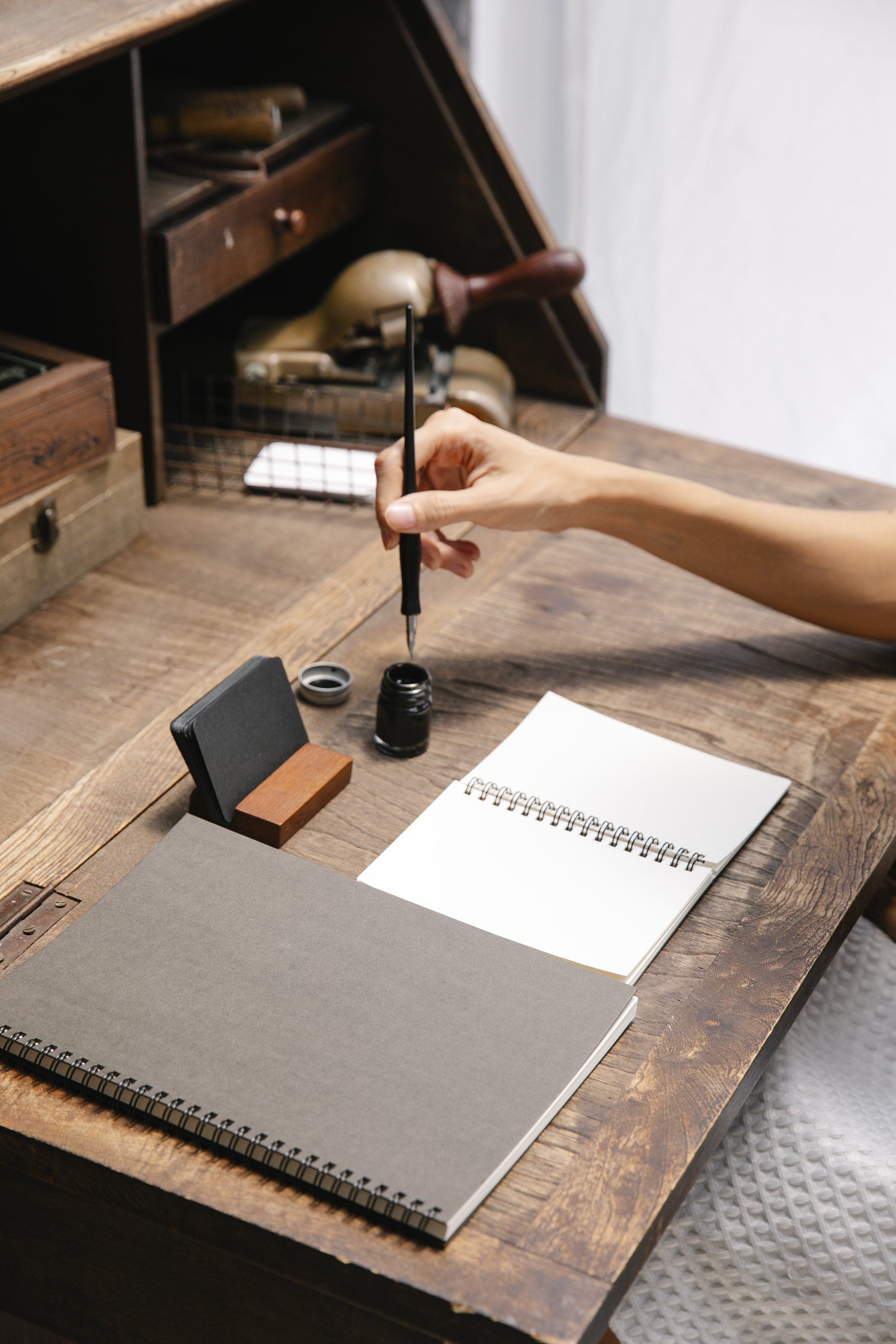 A person is writing in a notebook on a wooden desk.