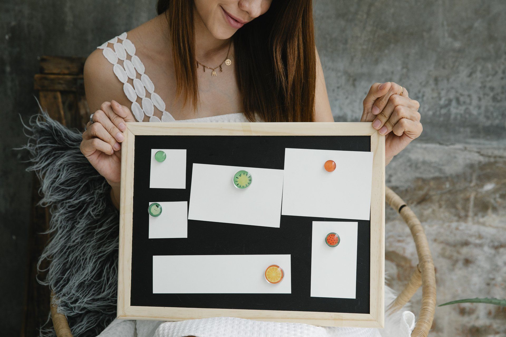 A woman is holding a blackboard with sticky notes on it.