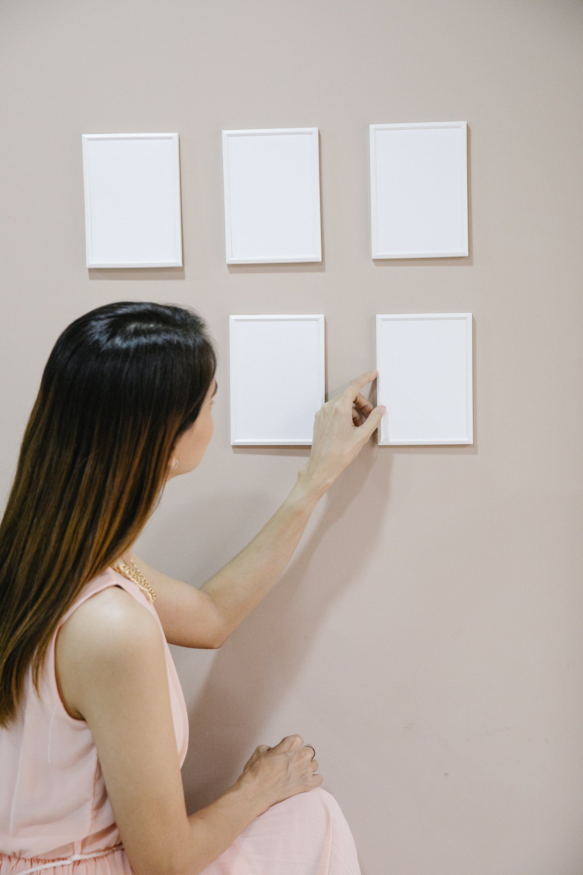 A woman is sitting on the floor looking at four white squares on a wall.