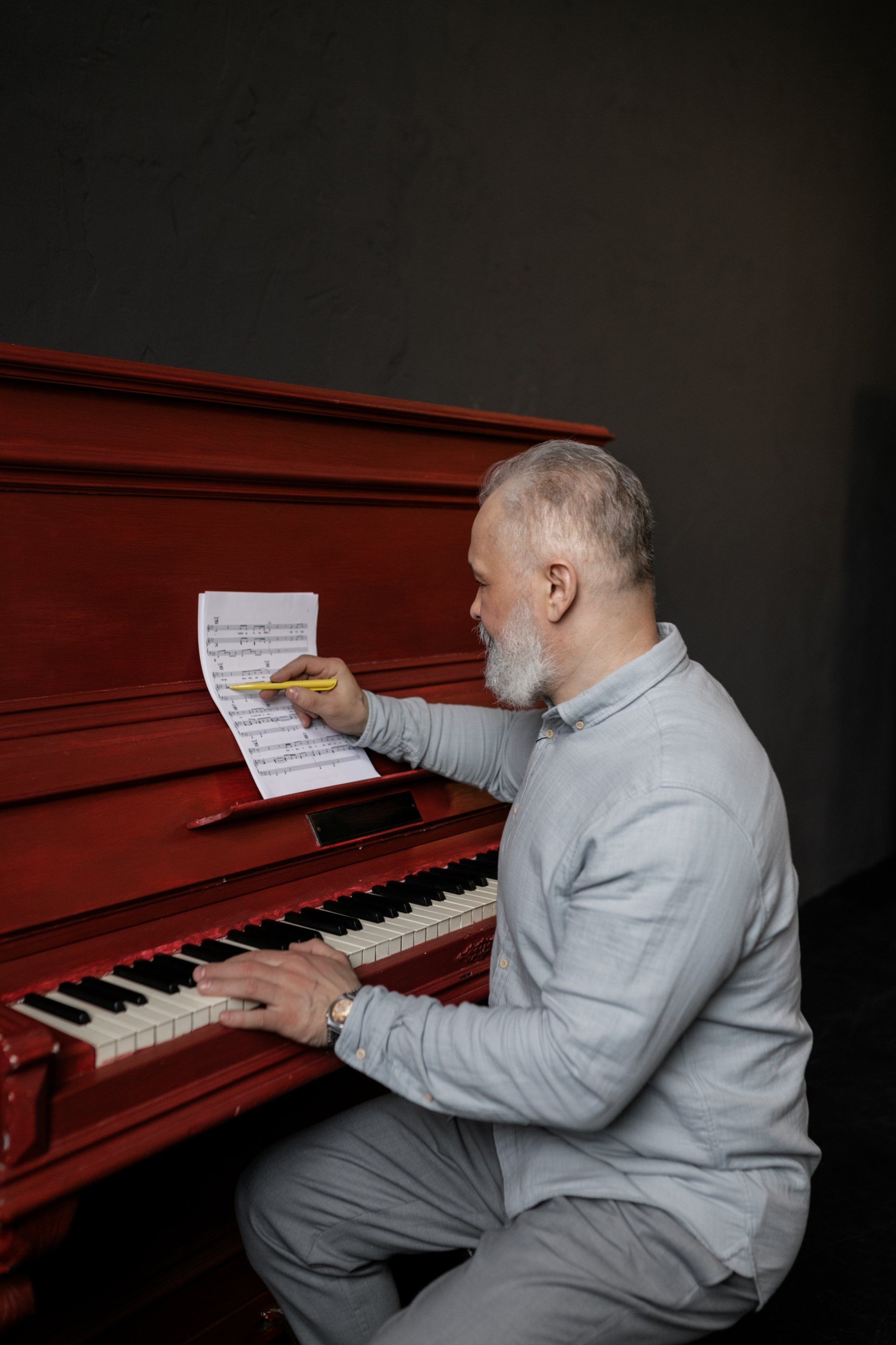 A man is sitting at a piano looking at sheet music.