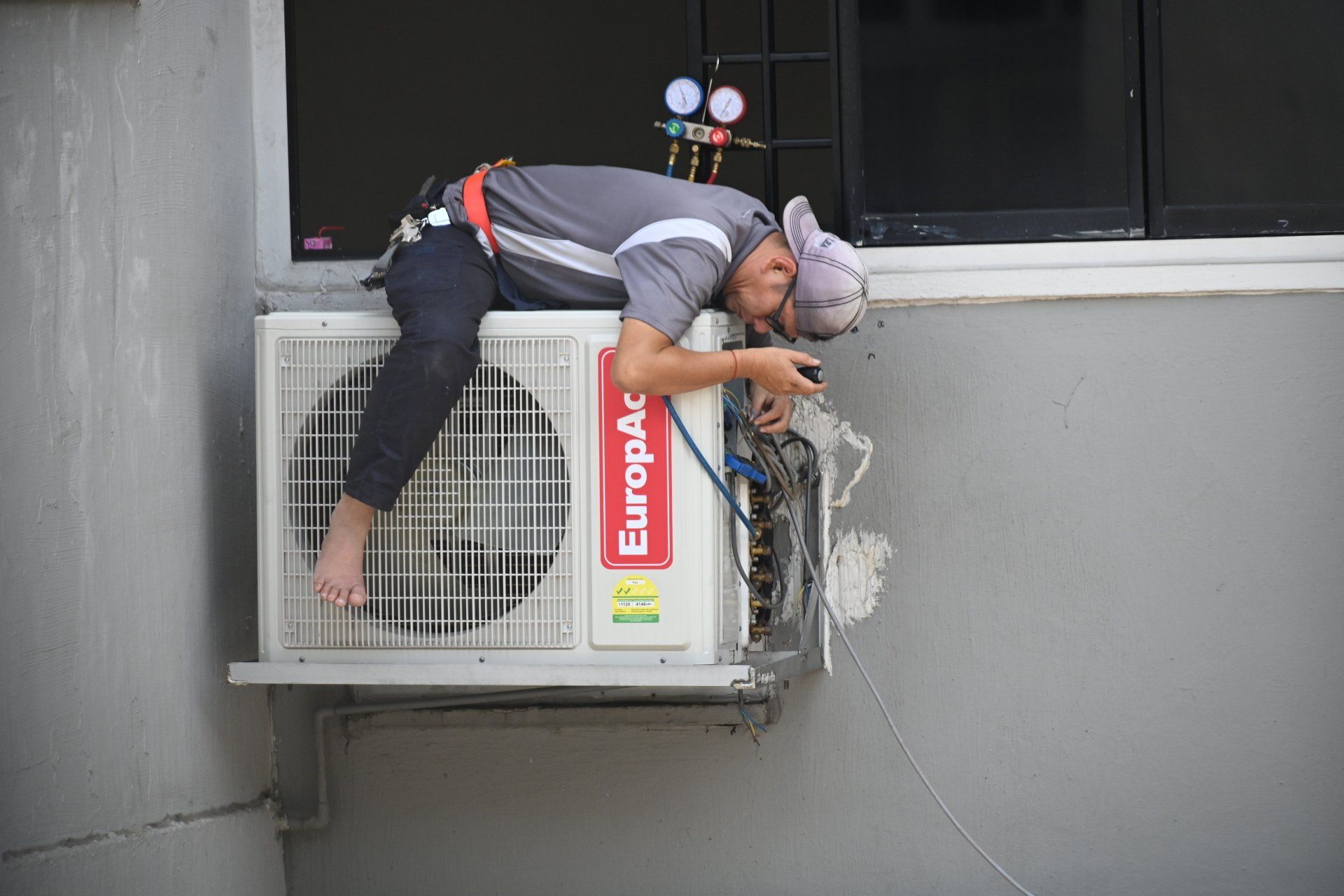 Person working on an air conditioner outside a building.