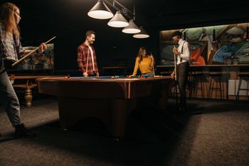 a group of people are playing pool in a pool hall .
