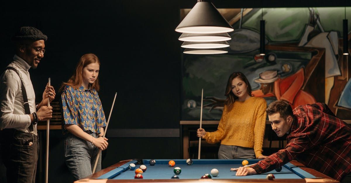 A group of people are playing pool in a pool hall at 4th and Park