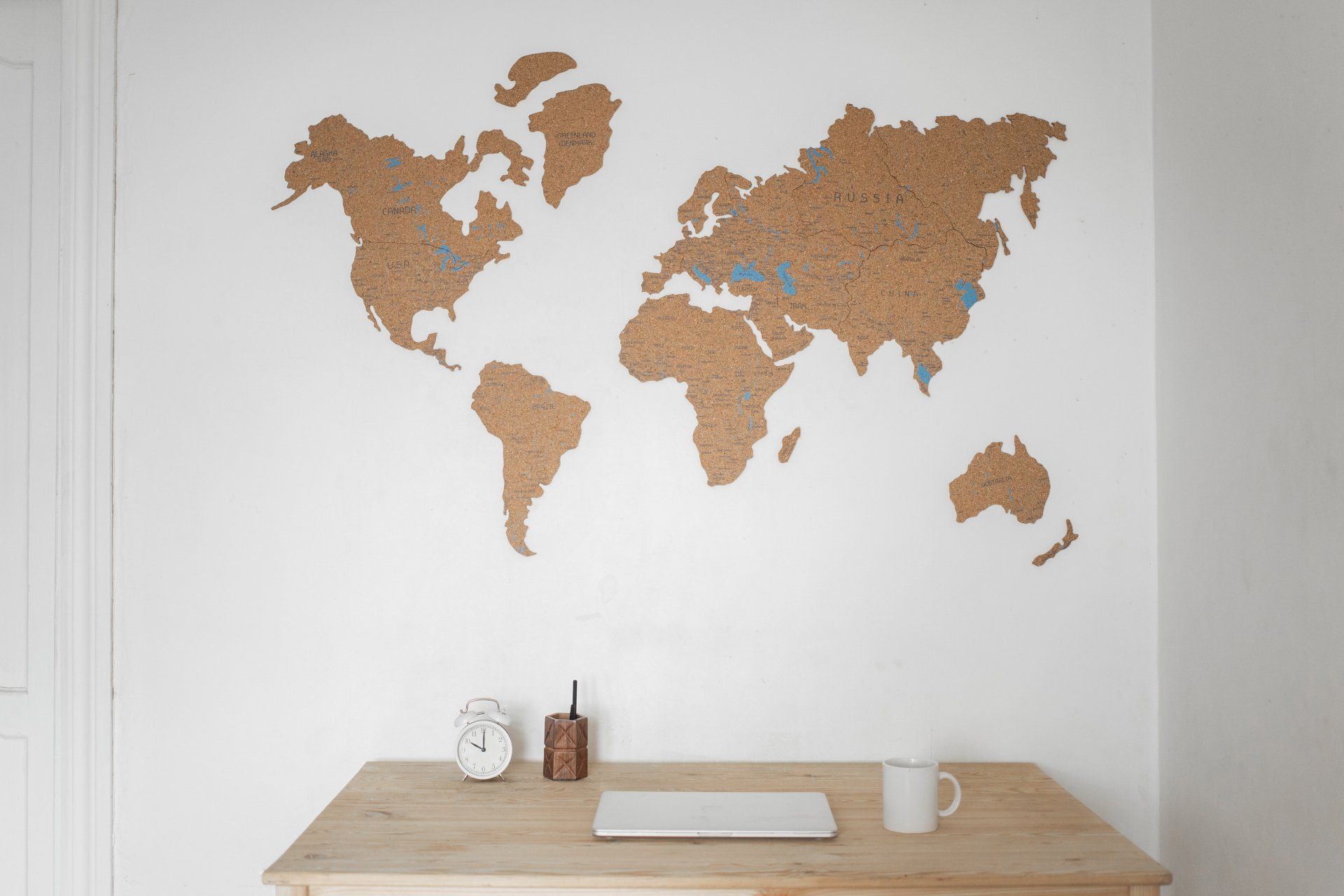 A desk with a laptop and a cork world map on the wall