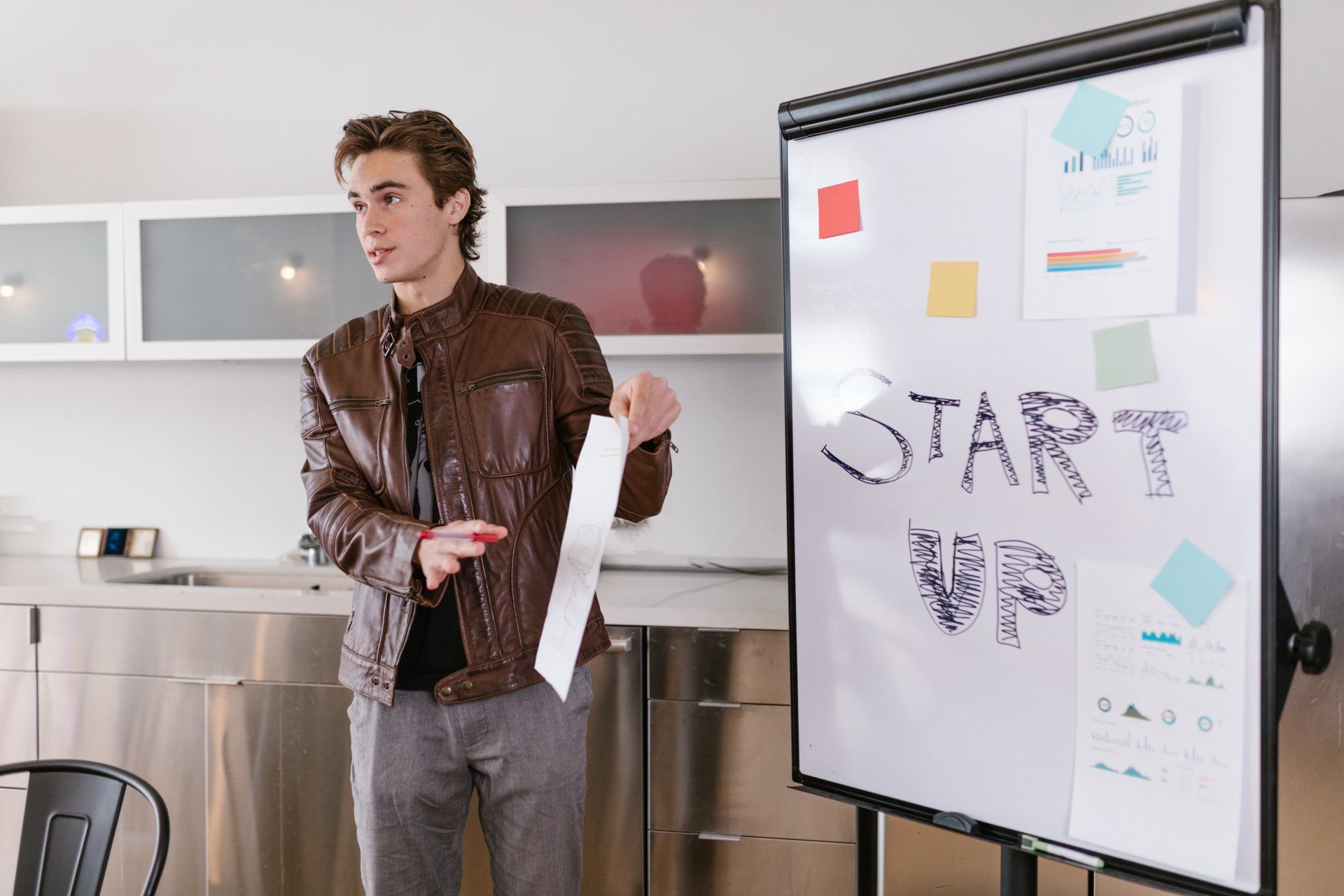 A man is giving a presentation in front of a whiteboard that says `` start up ''.