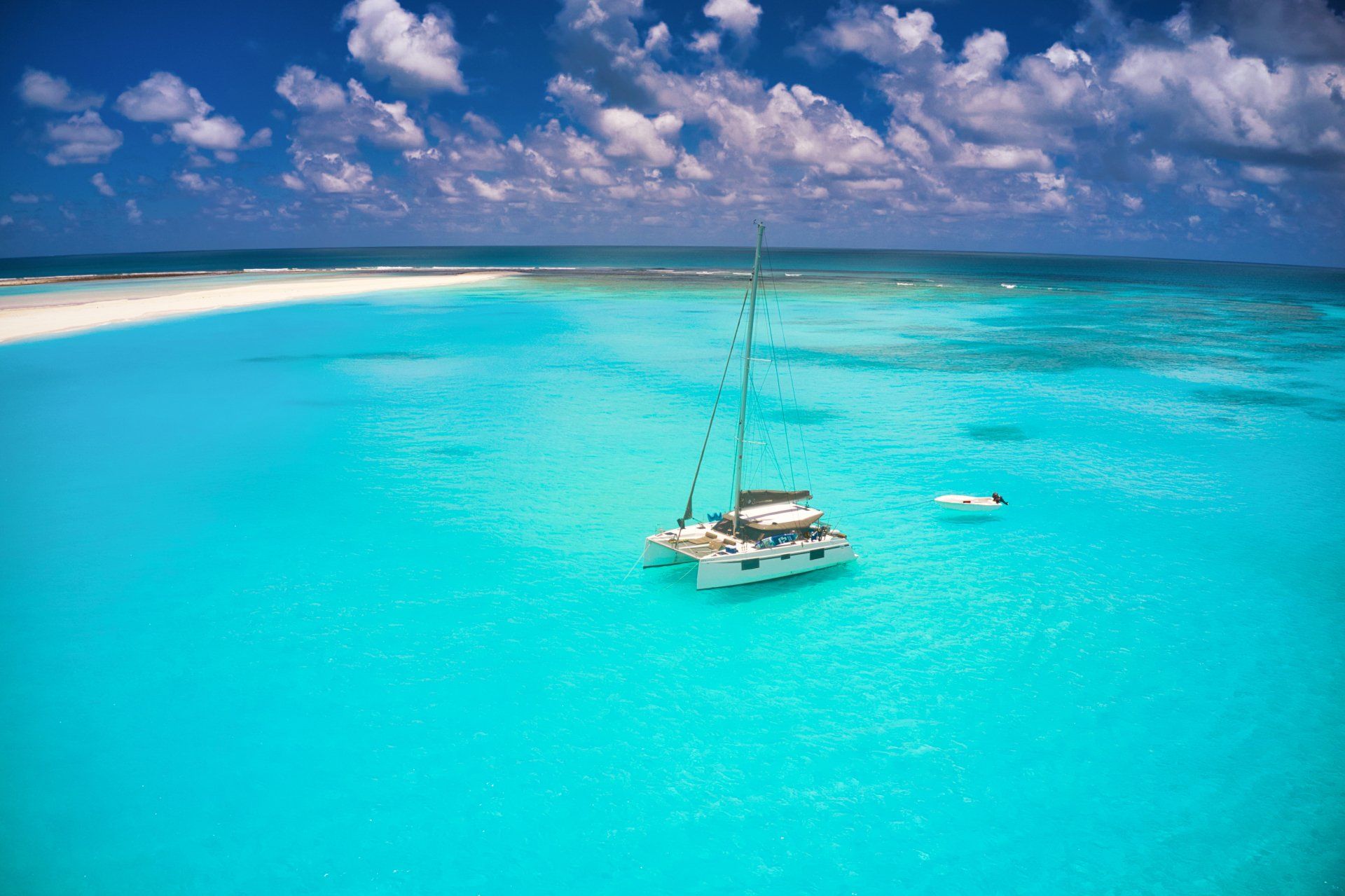 A sailboat is floating on top of a turquoise ocean.