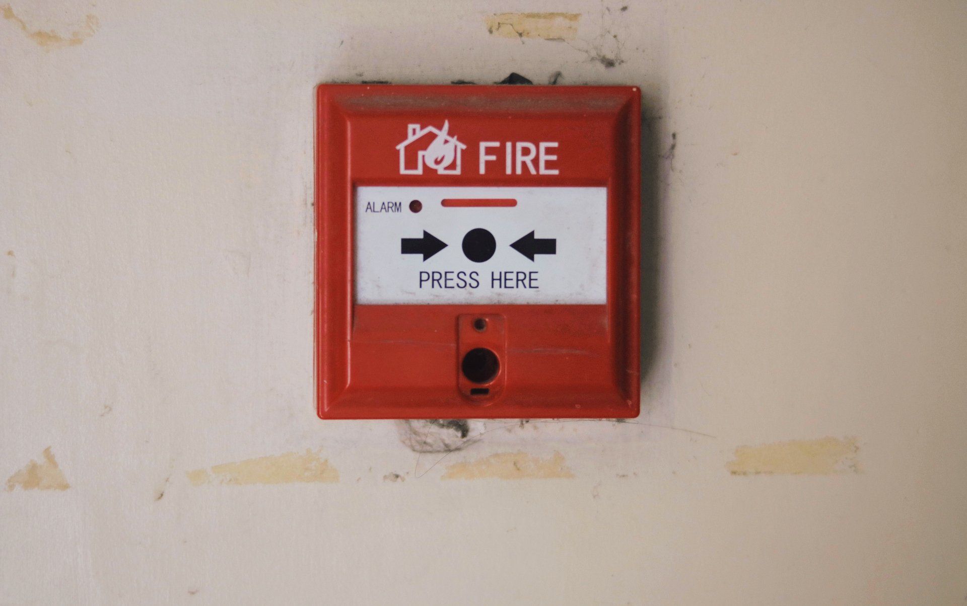 a red fire alarm button on a white wall