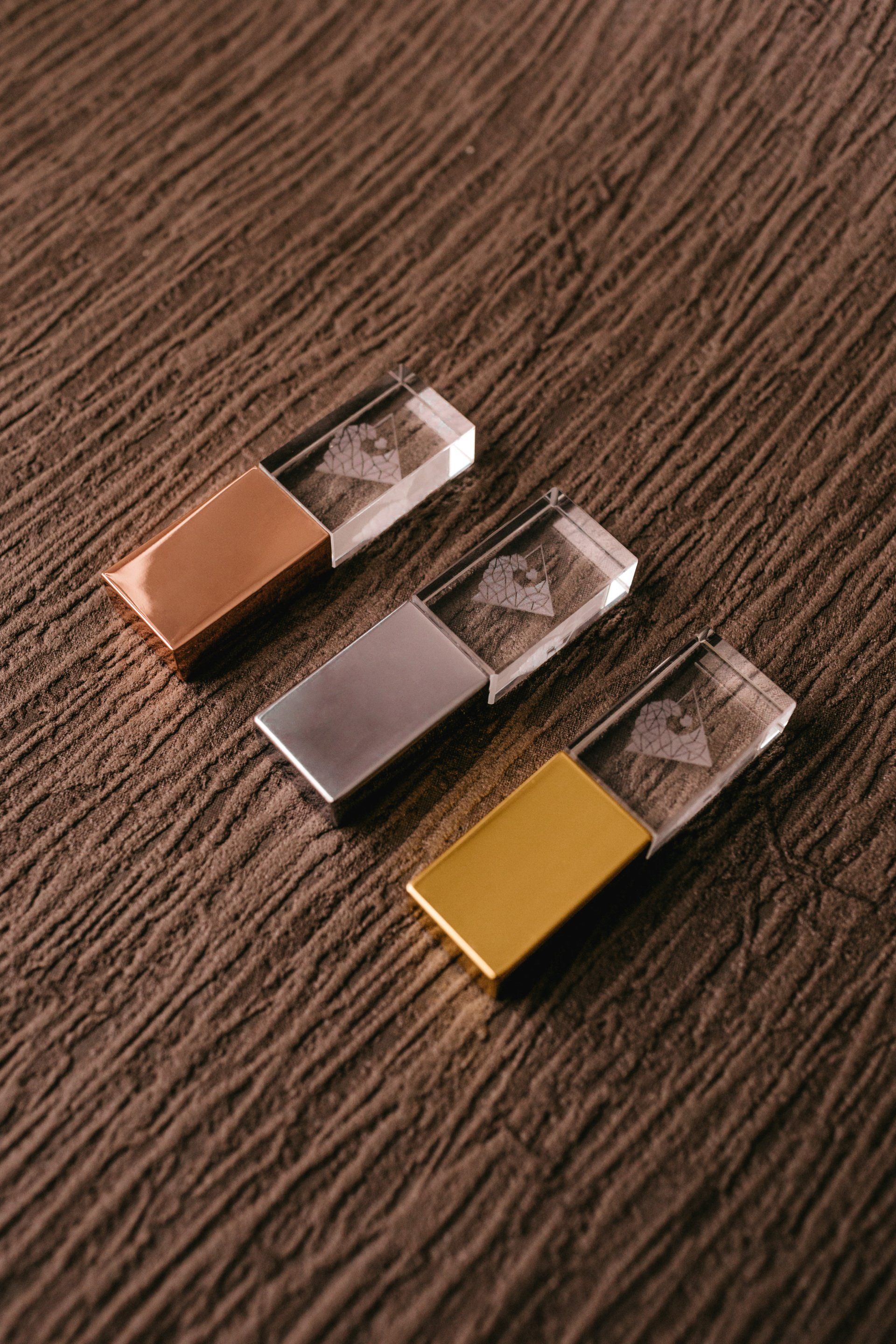 Three different colored flash drives are sitting on a wooden table.