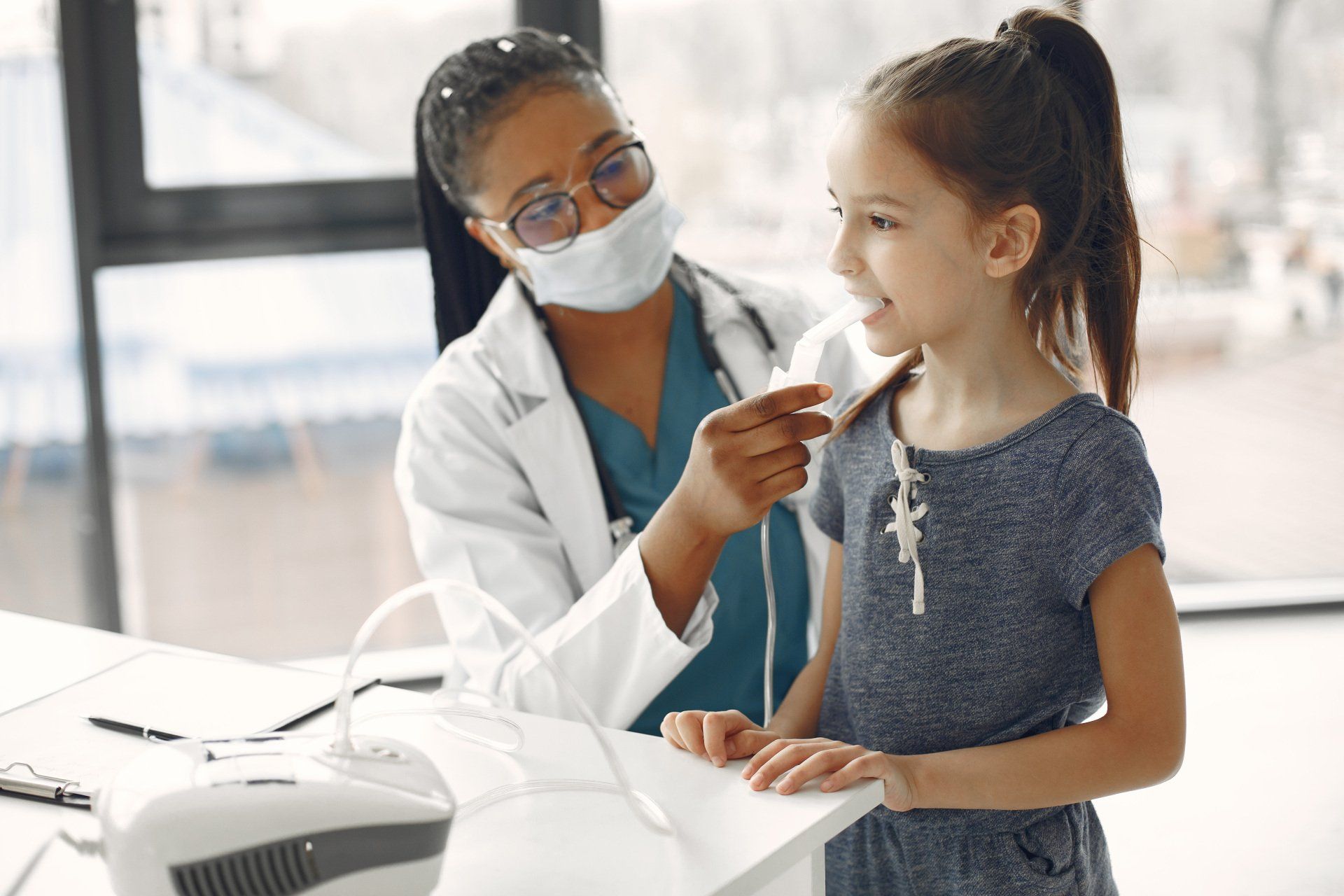 A doctor is using an inhaler on a little girl.