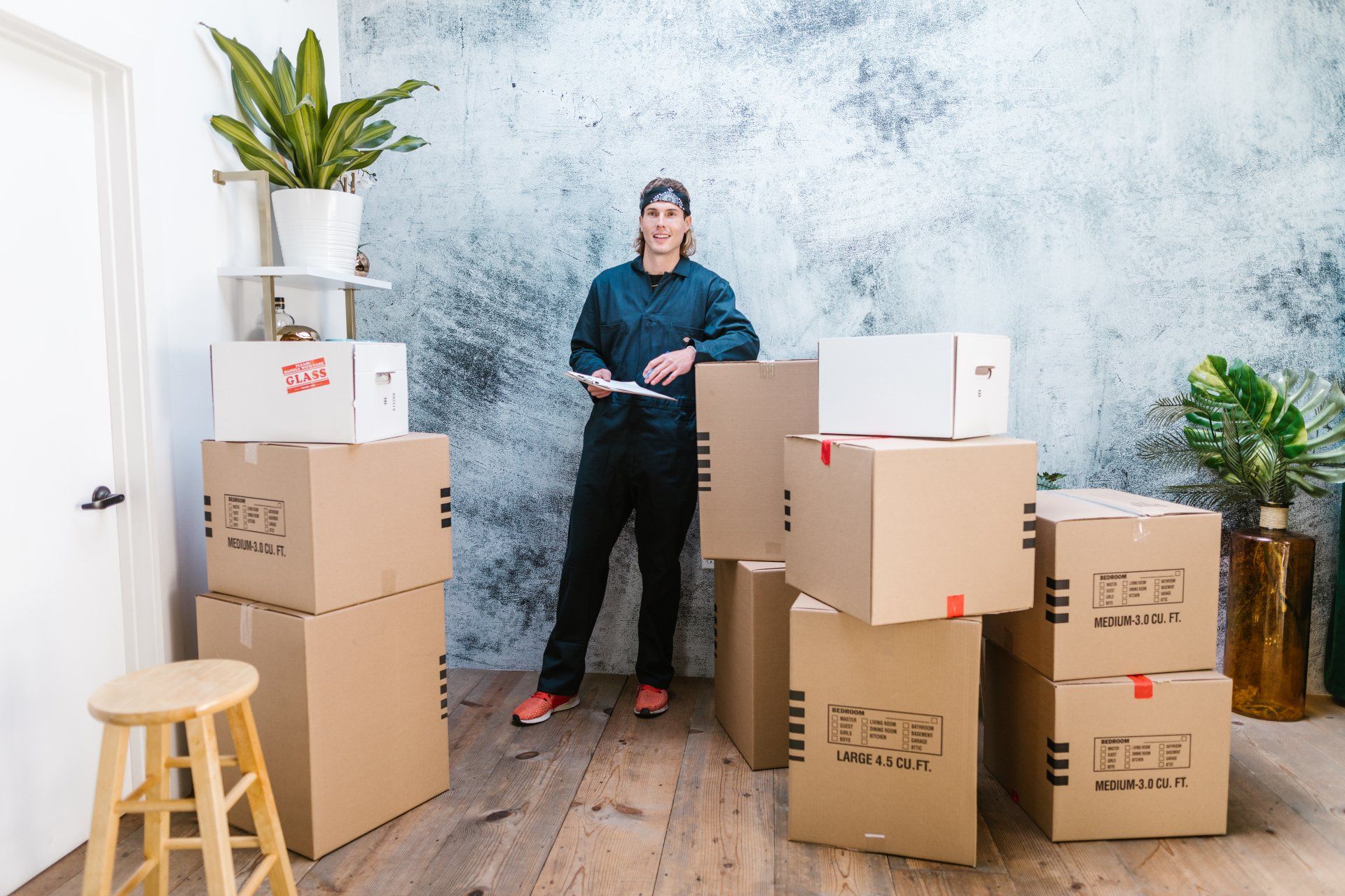 Un homme se tient à côté d'une pile de cartons dans une pièce.