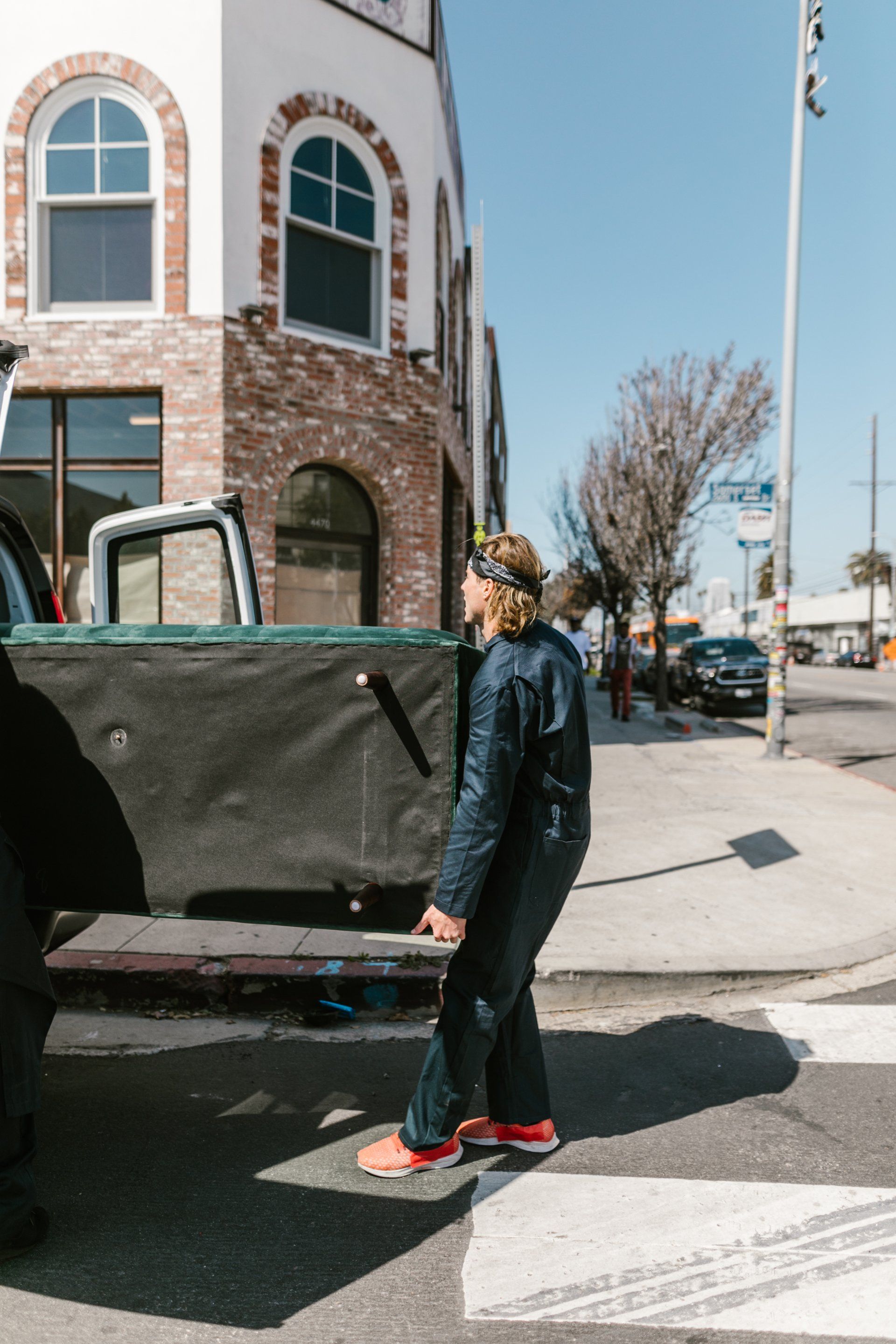 A man is loading a couch into the back of a truck.