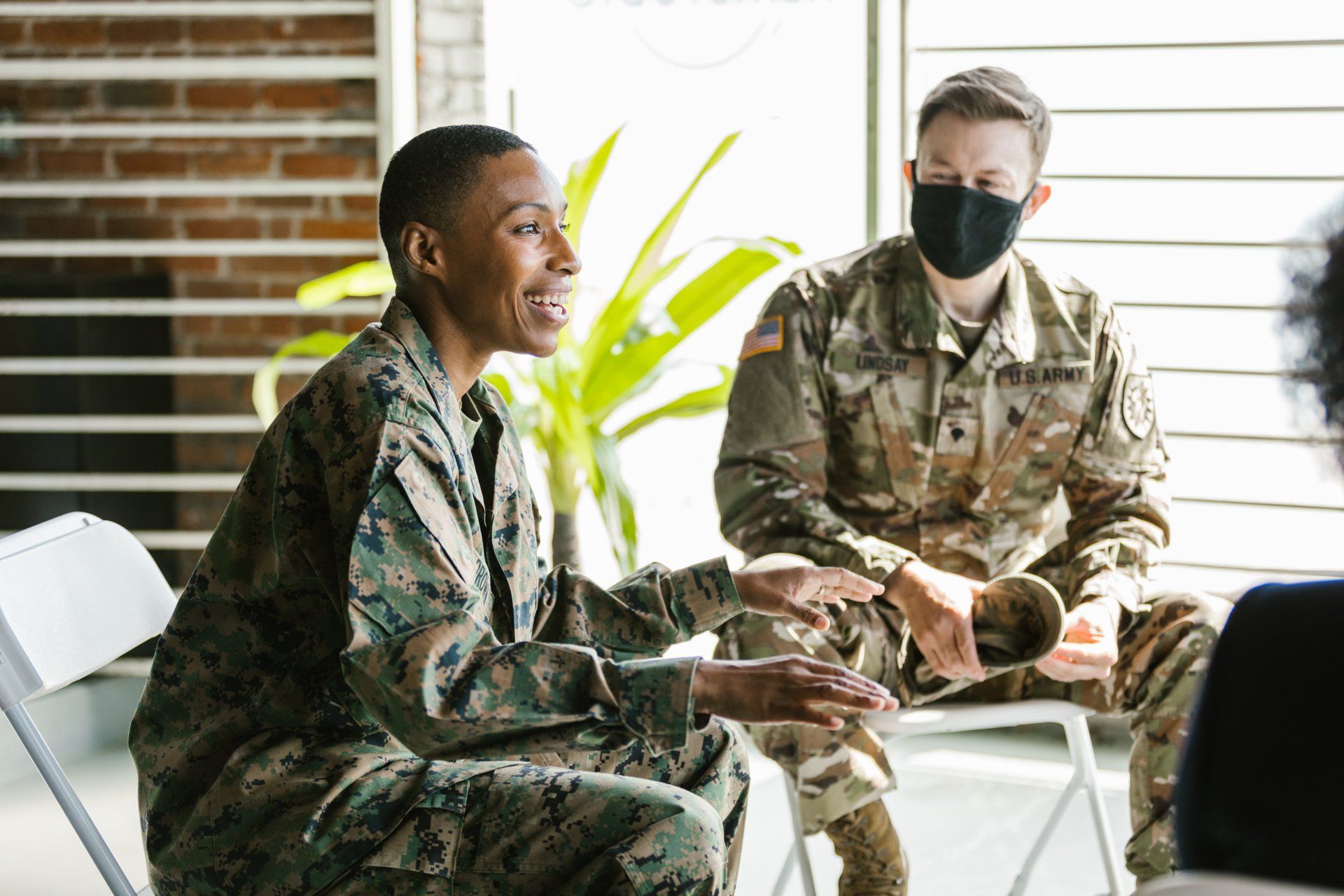 Two soldiers wearing masks are sitting in a circle talking to each other.