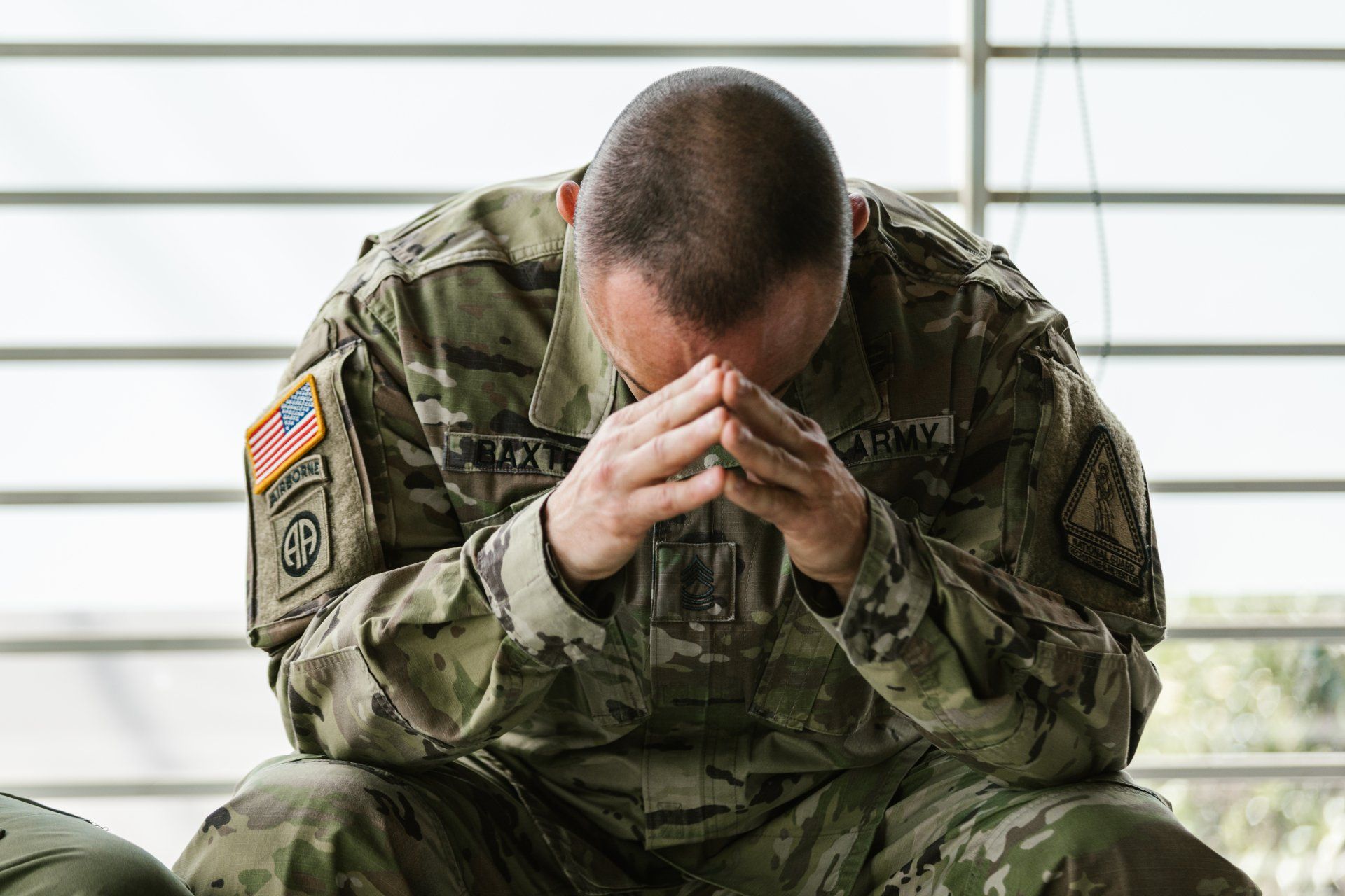 A soldier is sitting down with his head in his hands.  ptsd and ketamine treatment