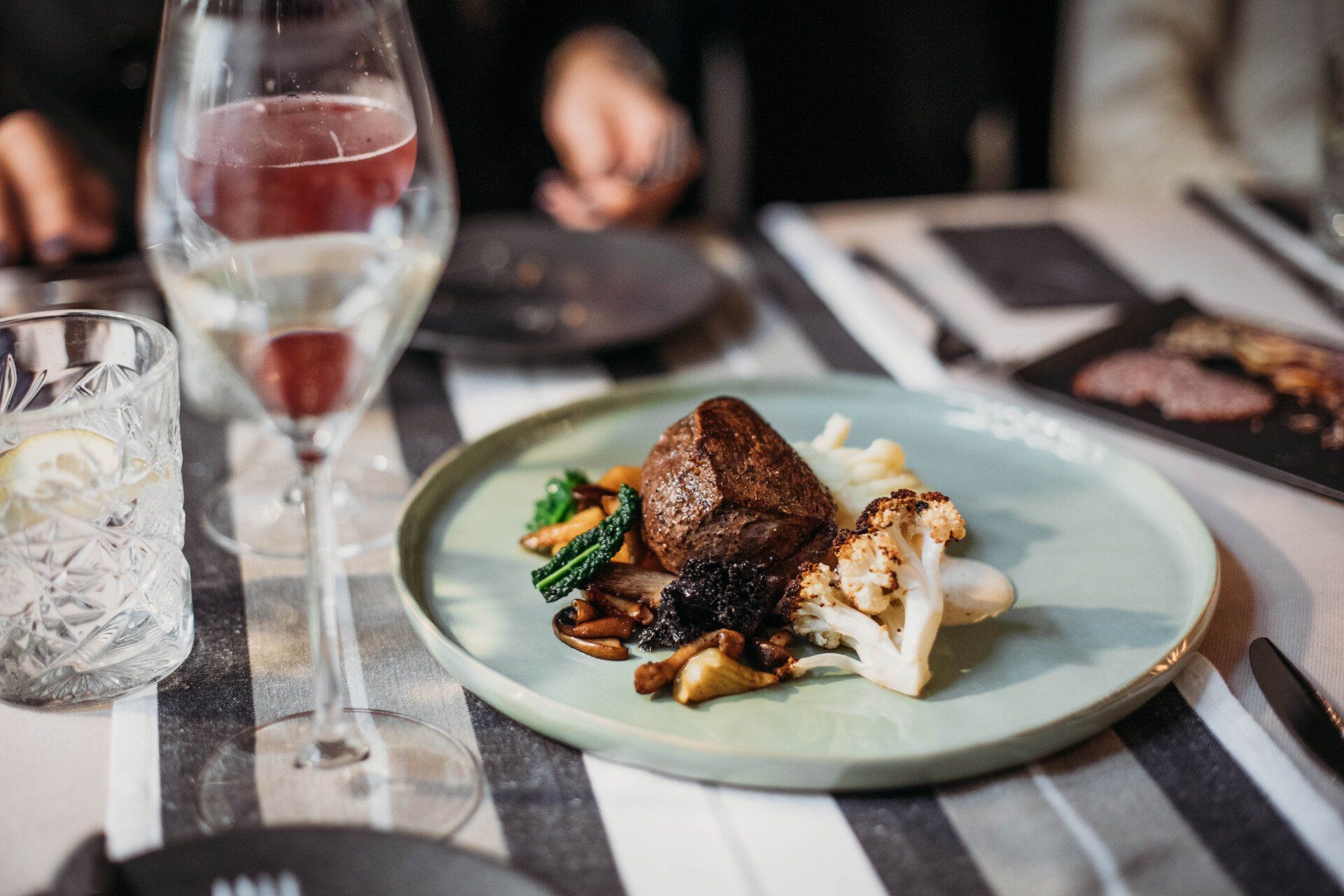 A plate of food with a glass of wine on a table.