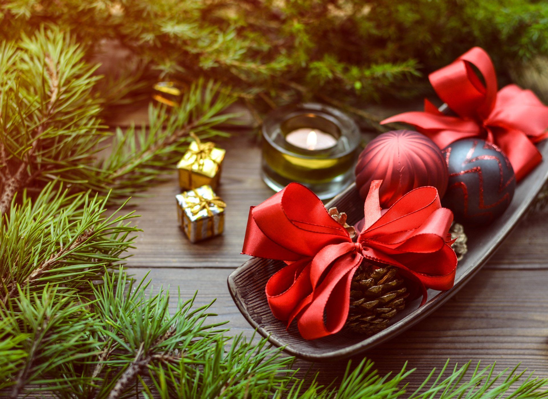 Christmas decorations in a bowl with a red bow on a wooden table.