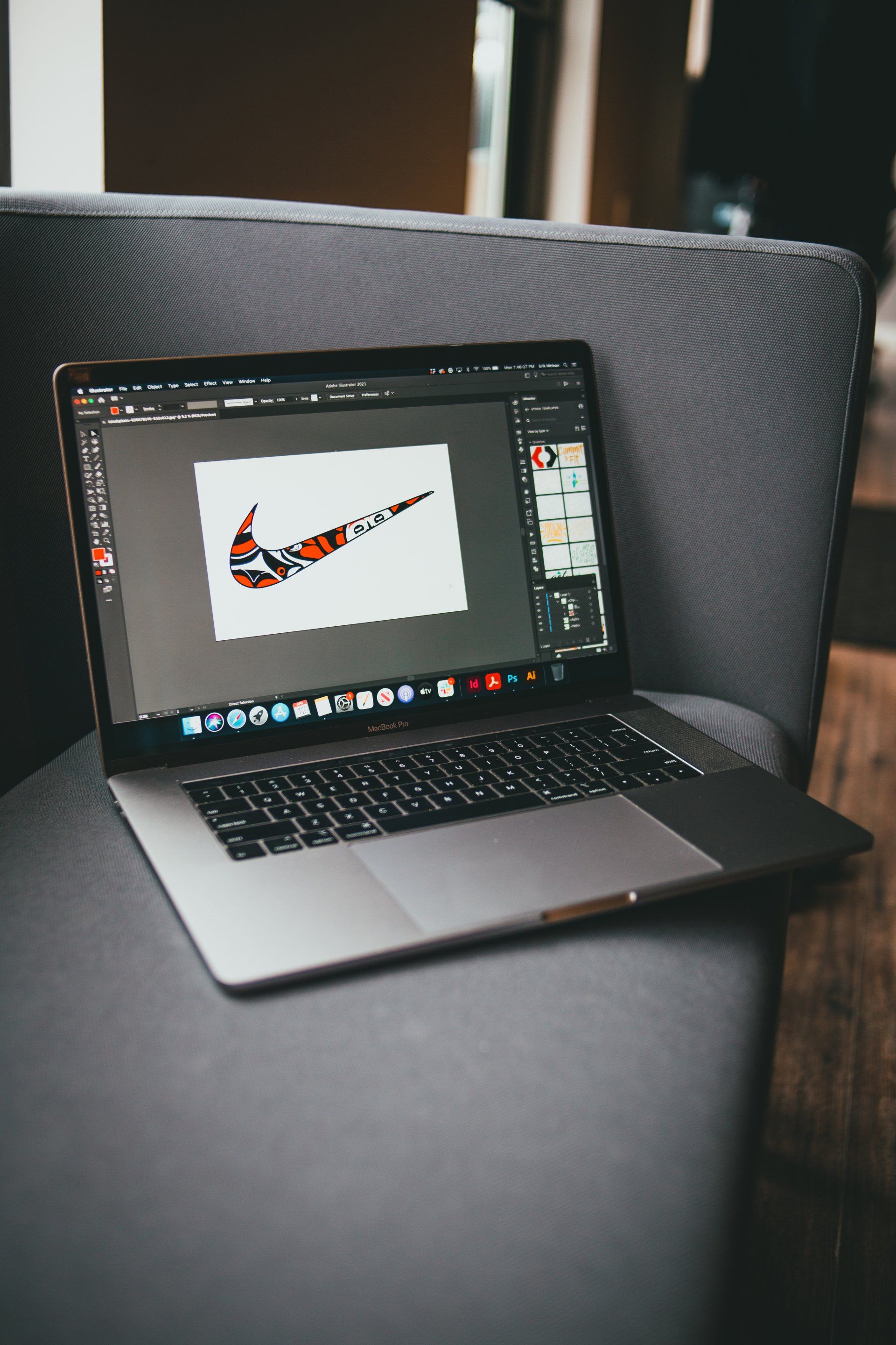 A laptop computer is sitting on a chair with a nike logo on the screen.