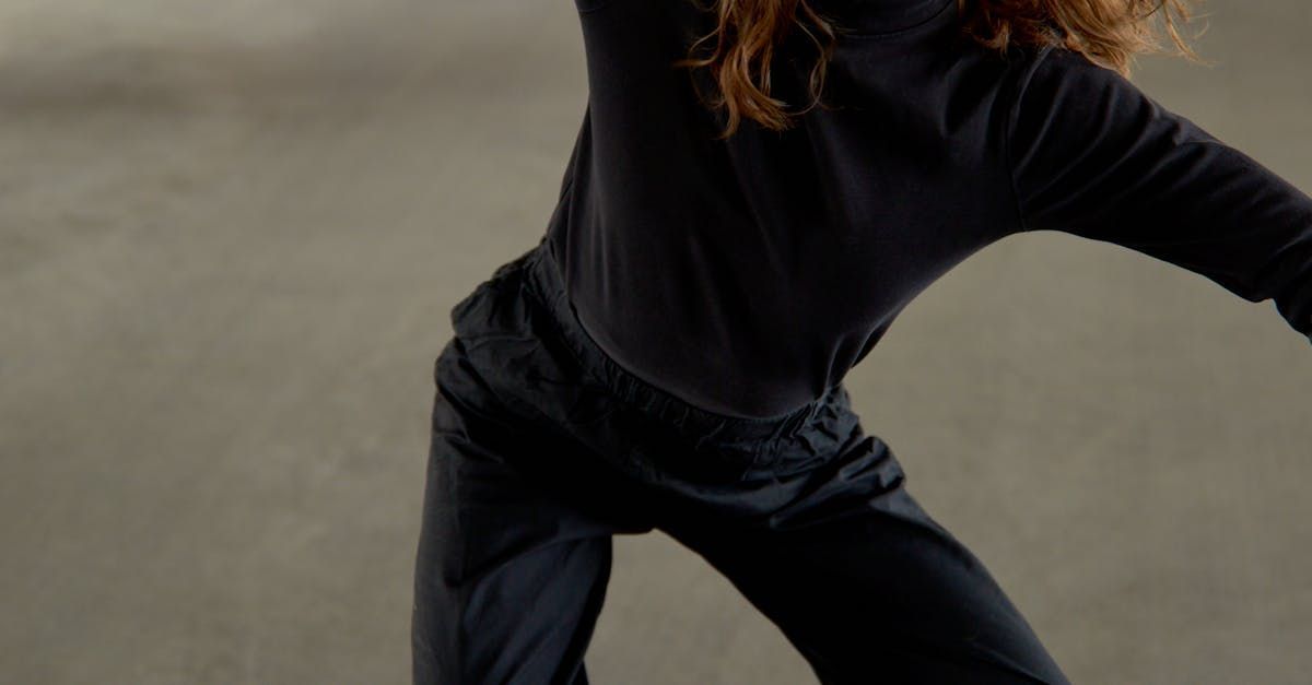 a woman in a black shirt and black pants is dancing .