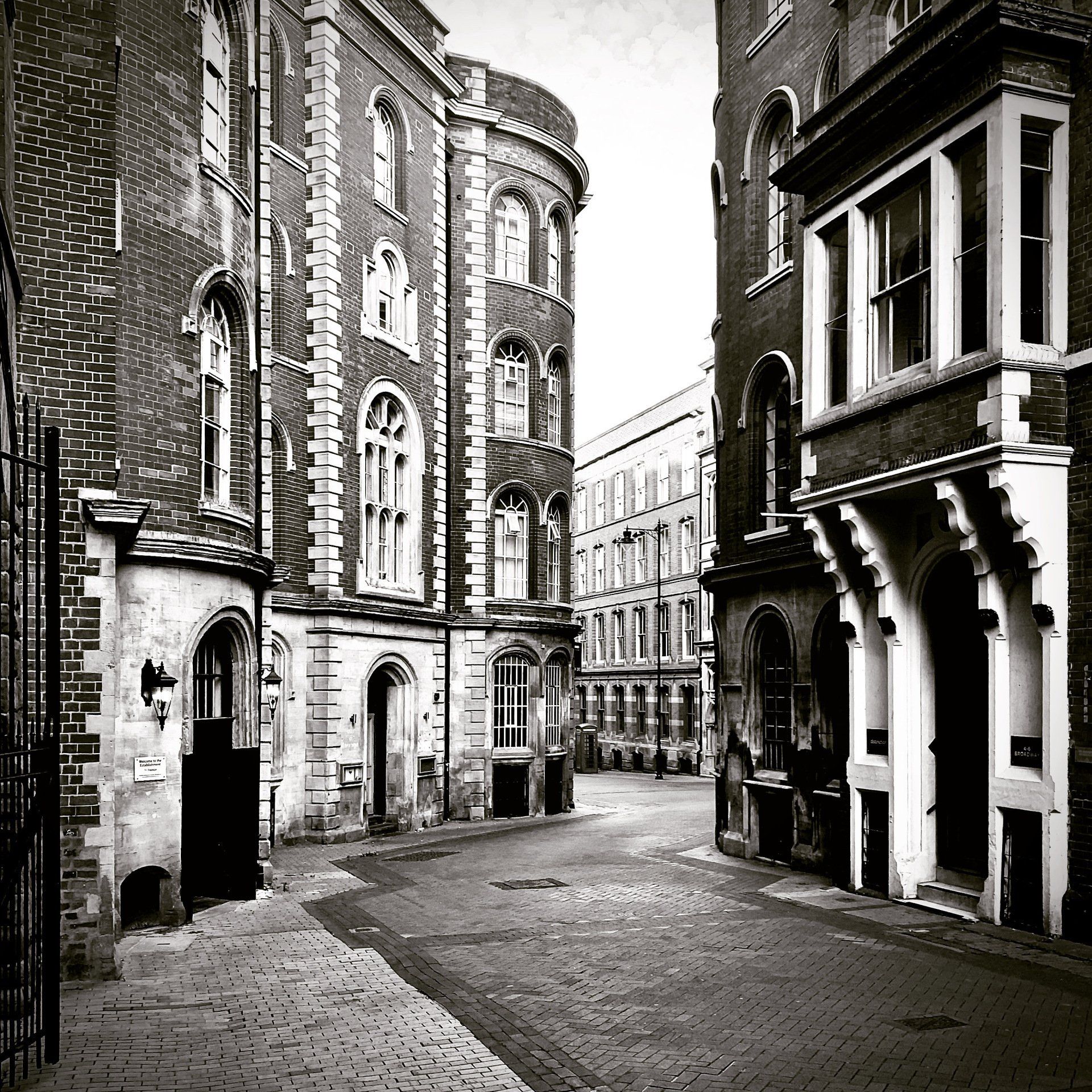 a black and white photo of a narrow street between two brick buildings
