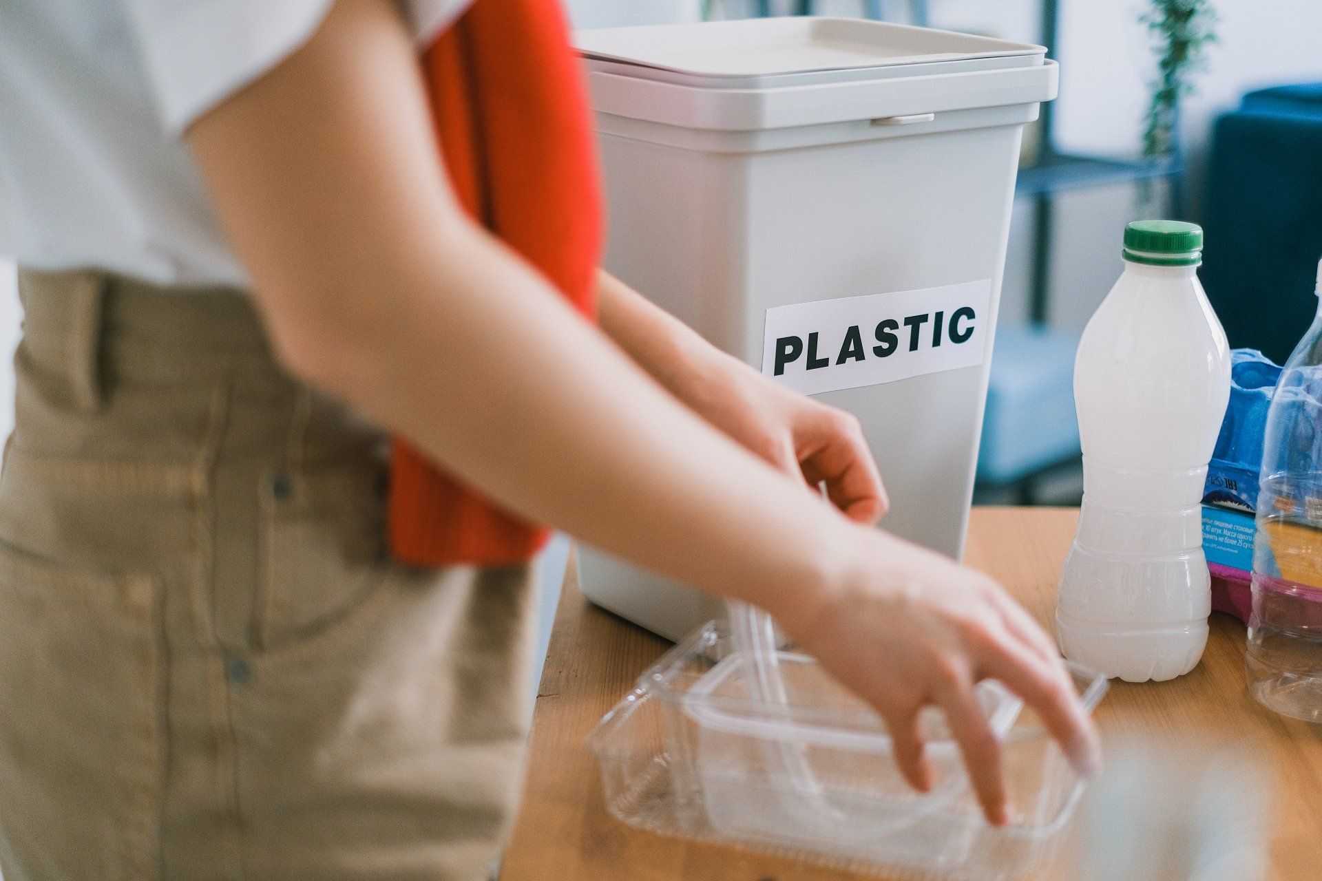 une personne jette des objets en plastique dans un bac de recyclage