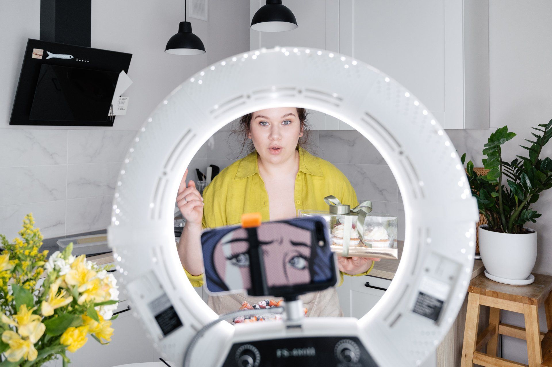 A woman is taking a picture of herself in front of a ring light.