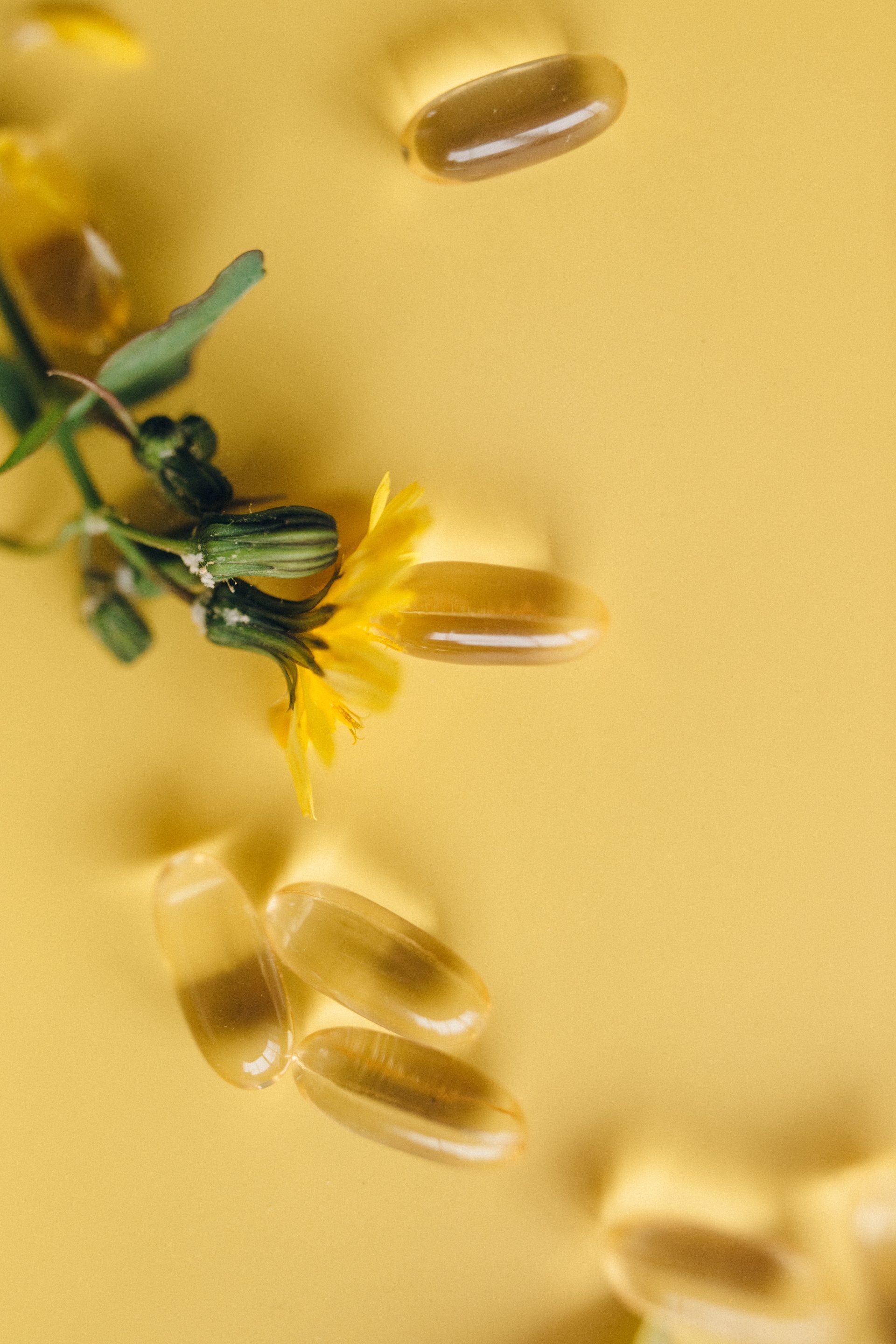 A bunch of pills and a yellow flower on a yellow background.