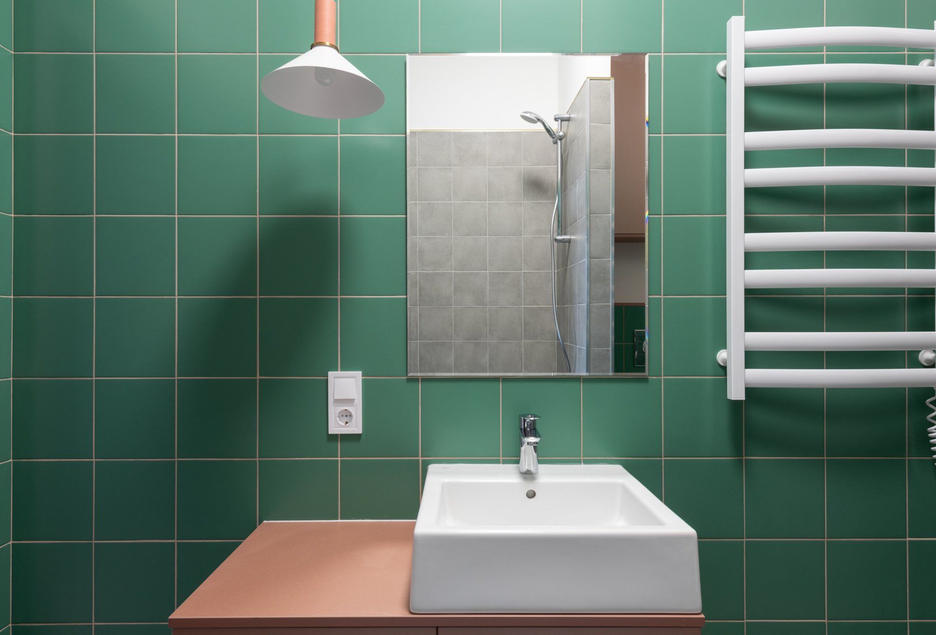 a bathroom with green tiles and a white towel rack