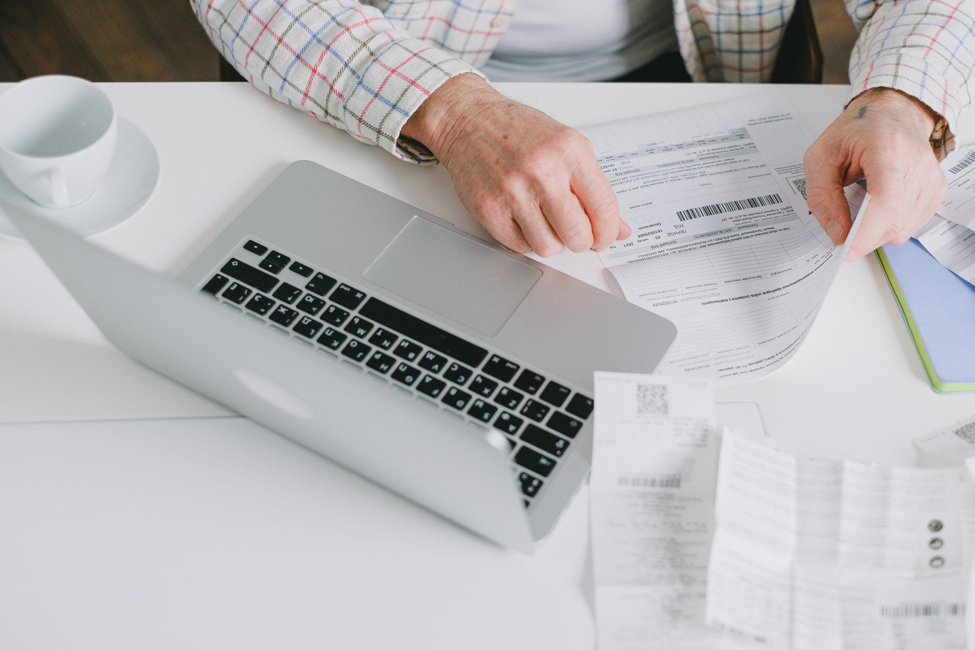 A man is sitting at a table with a laptop and papers.