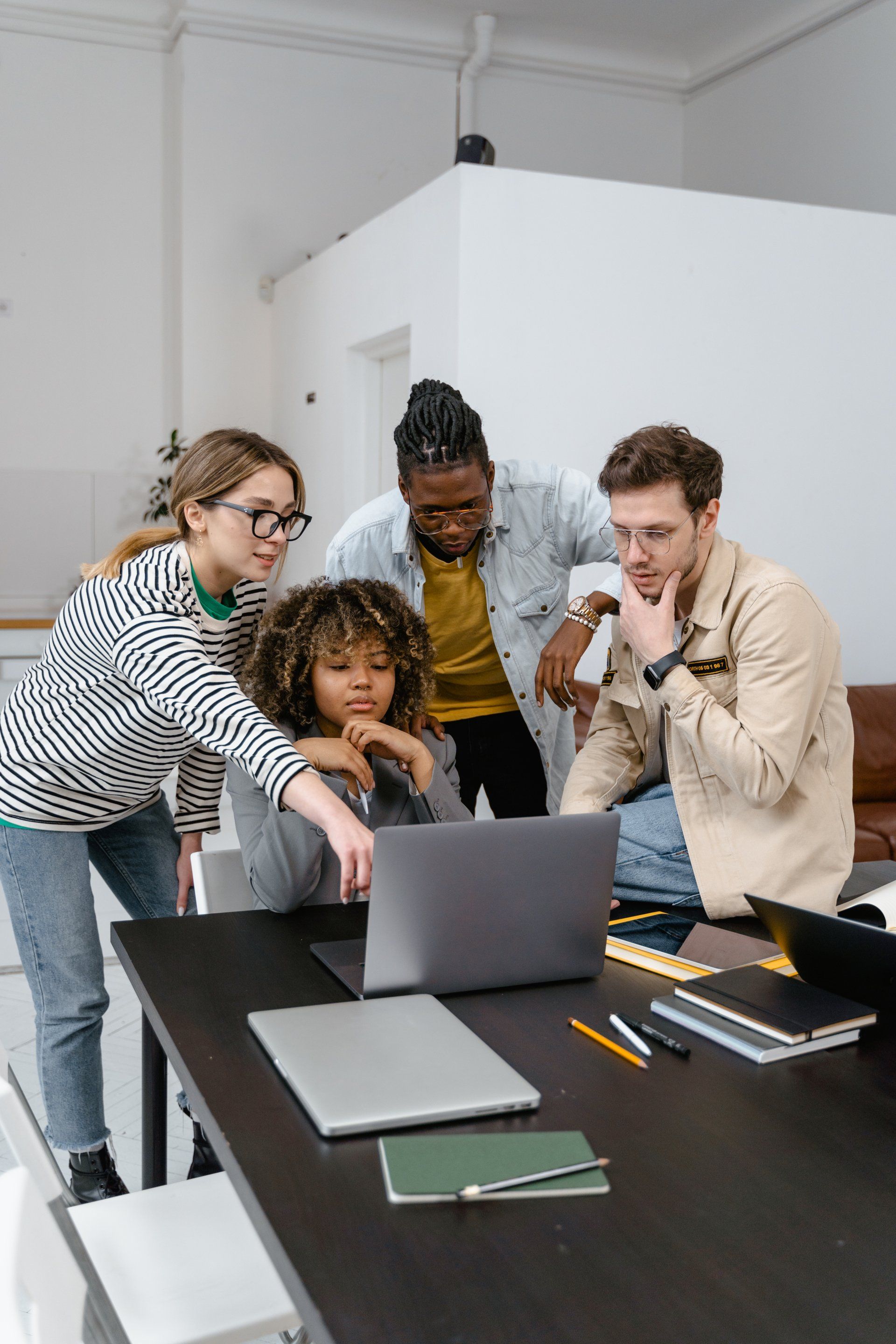 Grupo de 4 pessoas olhando para a tela do computador em um escritório