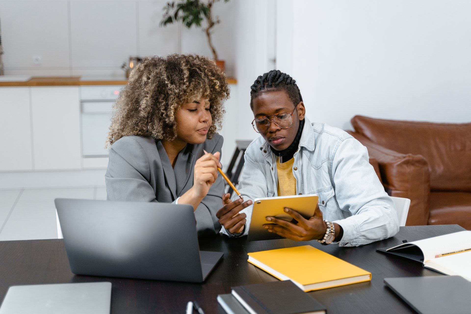A man and a woman are sitting at a table looking at a tablet.