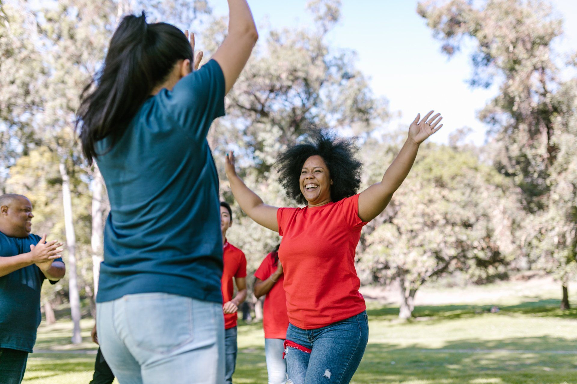 A group of people are dancing in a park.