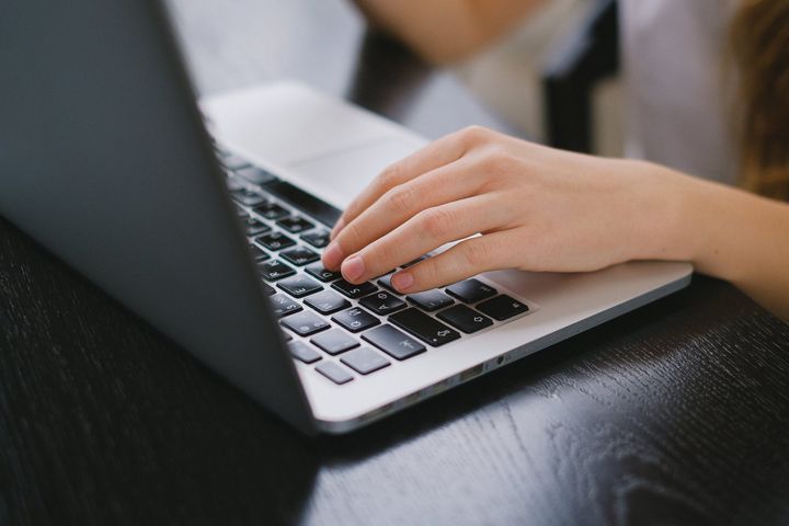 De hand van een vrouw typt op het toetsenbord van een laptop