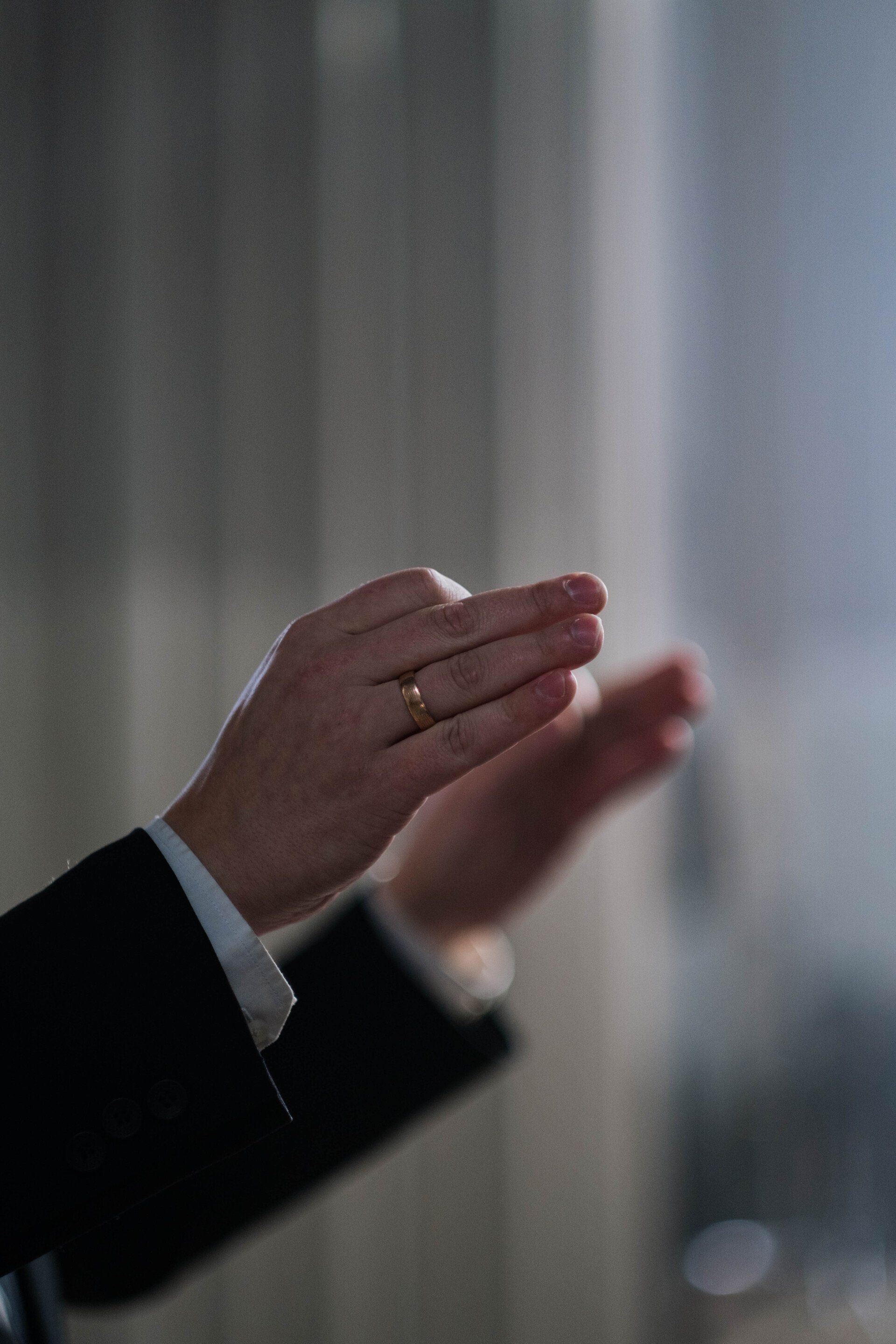 A man wearing a wedding ring is clapping his hands.