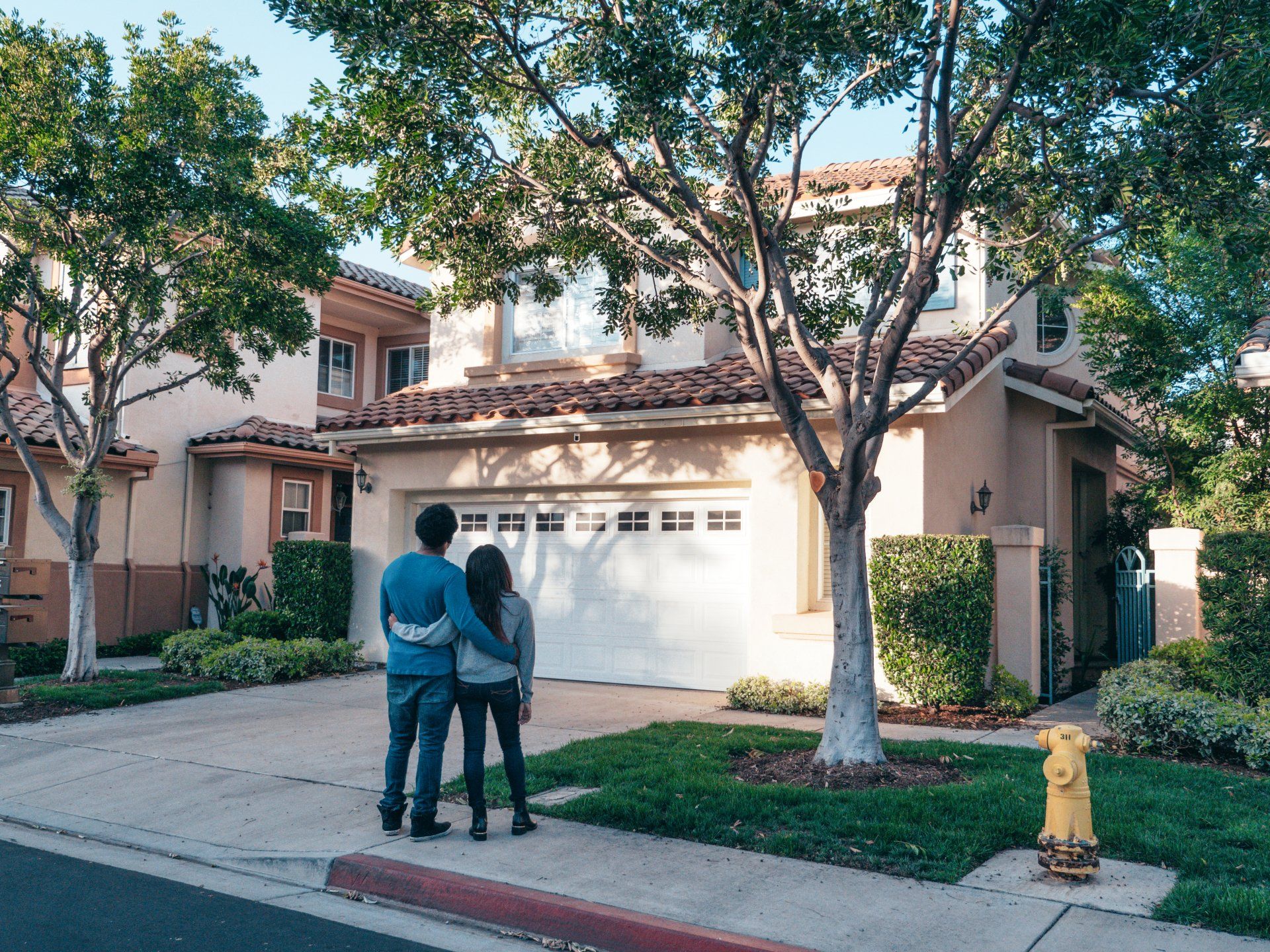 a man and woman are standing in front of a house .