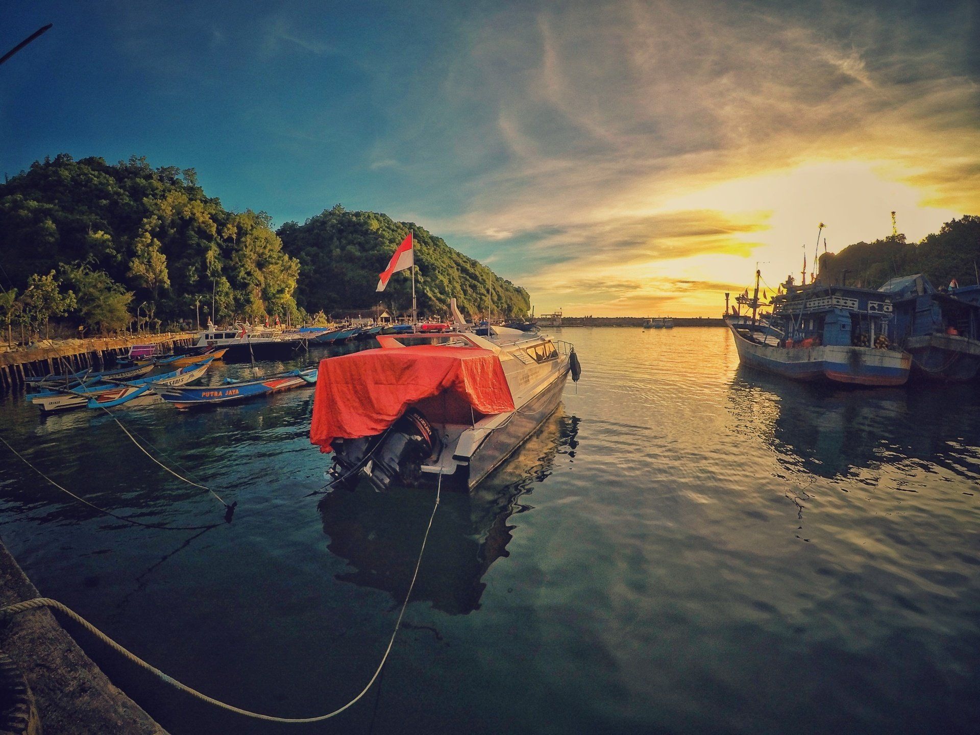 A boat is docked in a harbor at sunset.