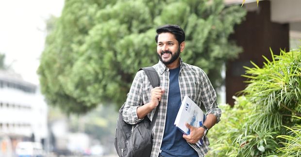 An international student is walking down the street with a backpack and books.