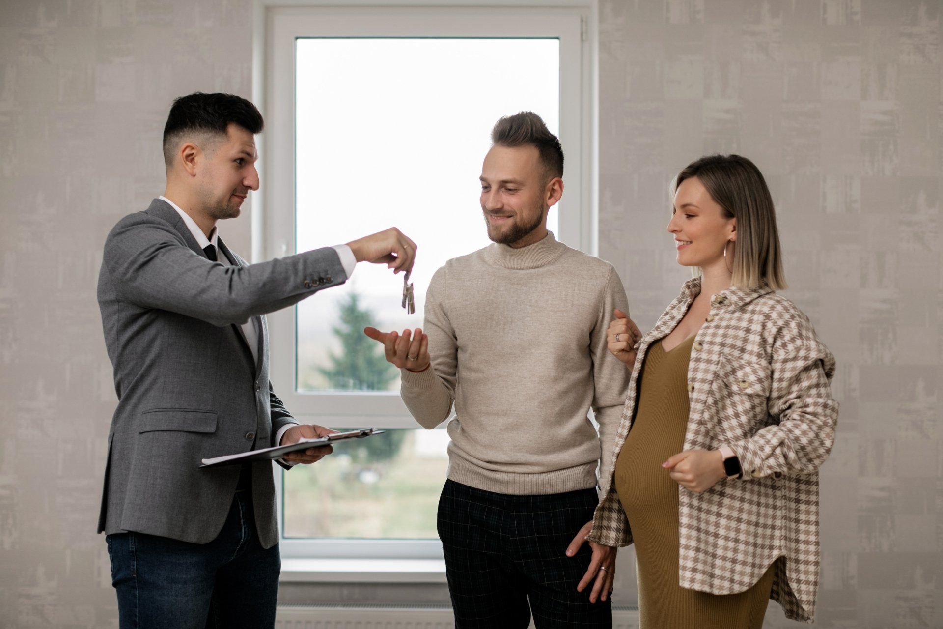 Photo of smart, tech-saavy Real Estate Agent handing keys to a couple's new home.