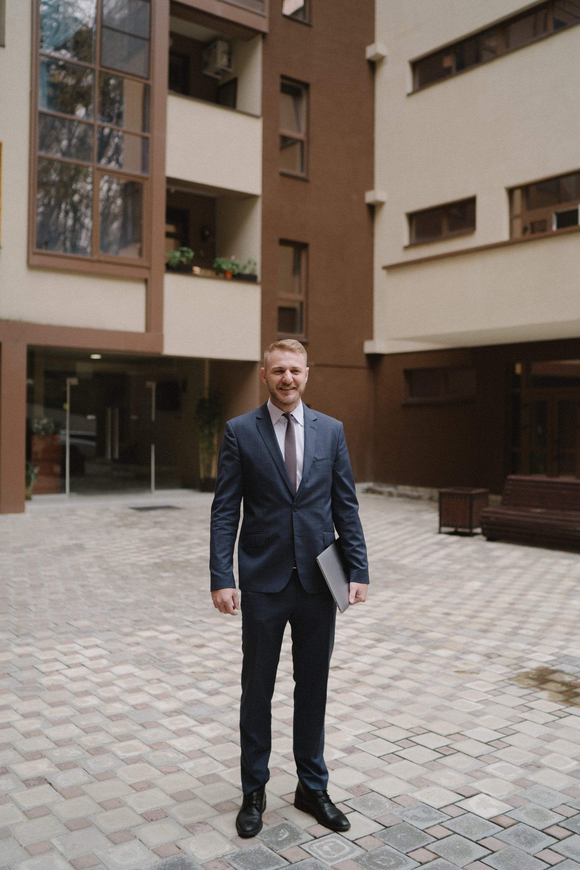 A man in a suit and tie is standing in front of a building.