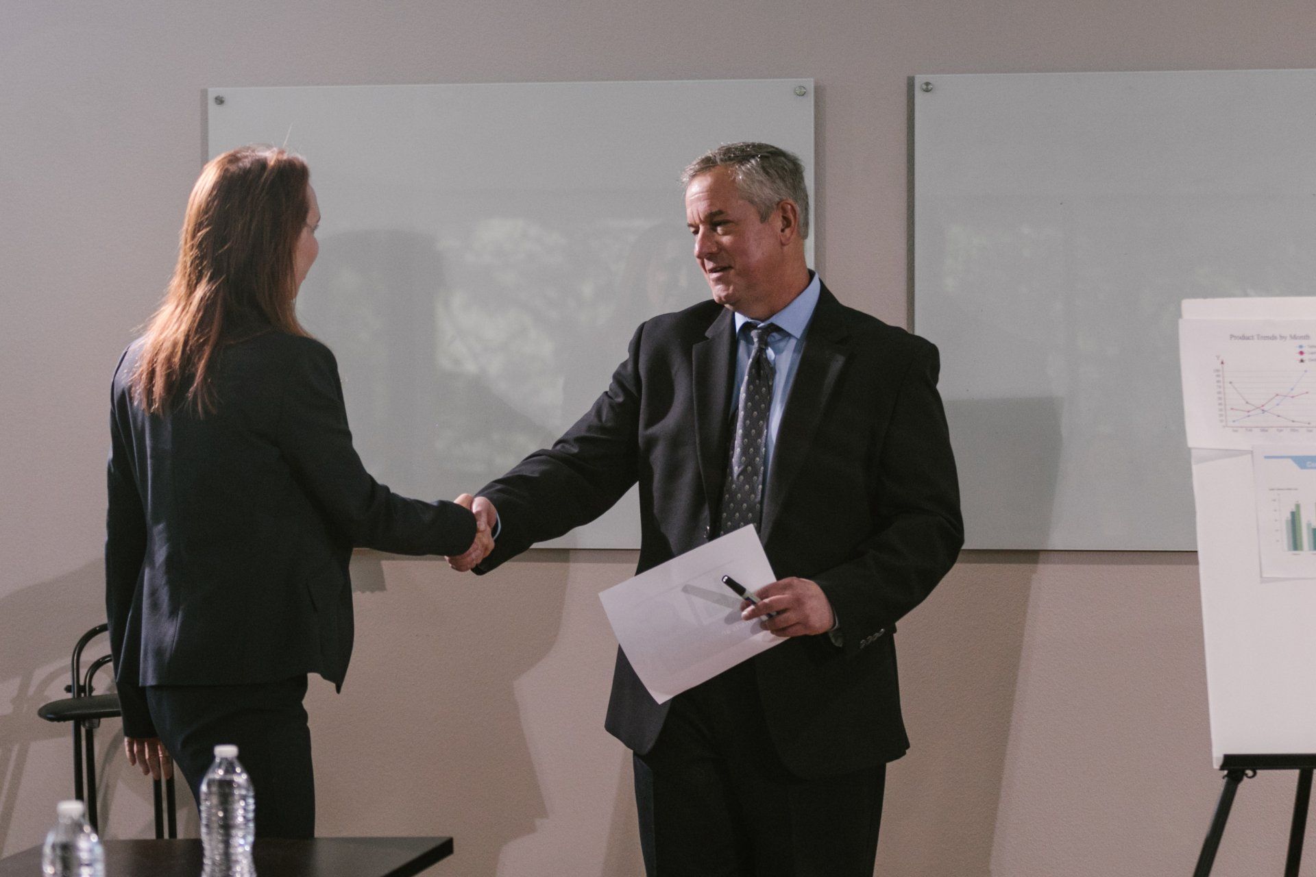 A man and a woman are shaking hands in a conference room.