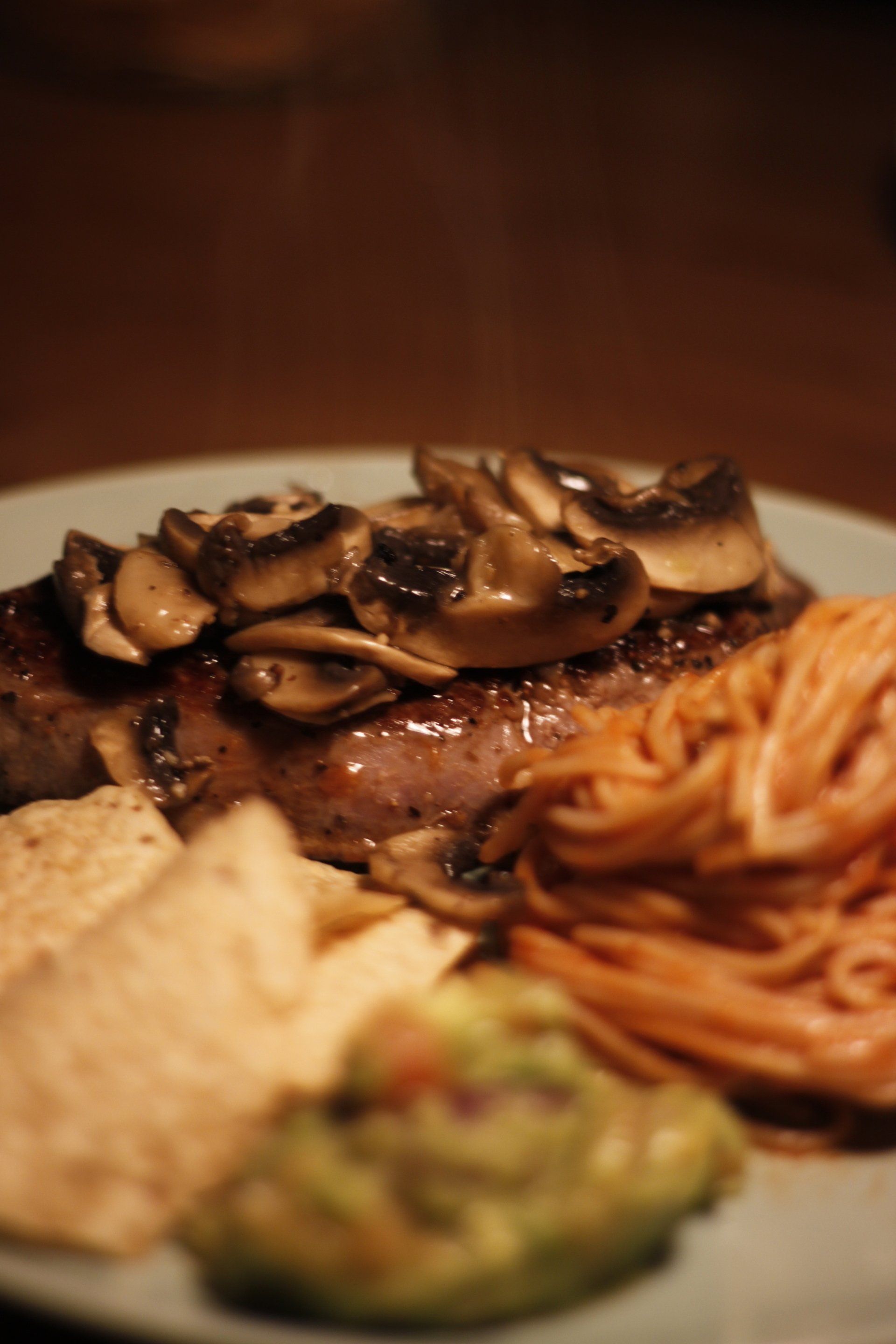 A plate of food with a steak noodles and guacamole