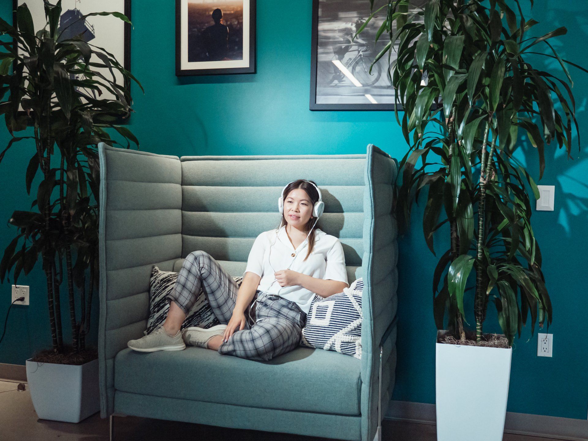 A woman is sitting on a couch wearing headphones.