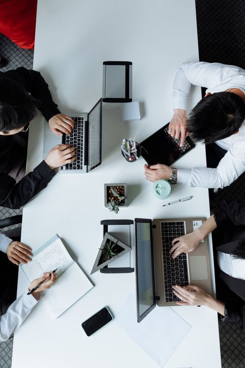 Un grupo de personas están sentadas en una mesa con computadoras portátiles.