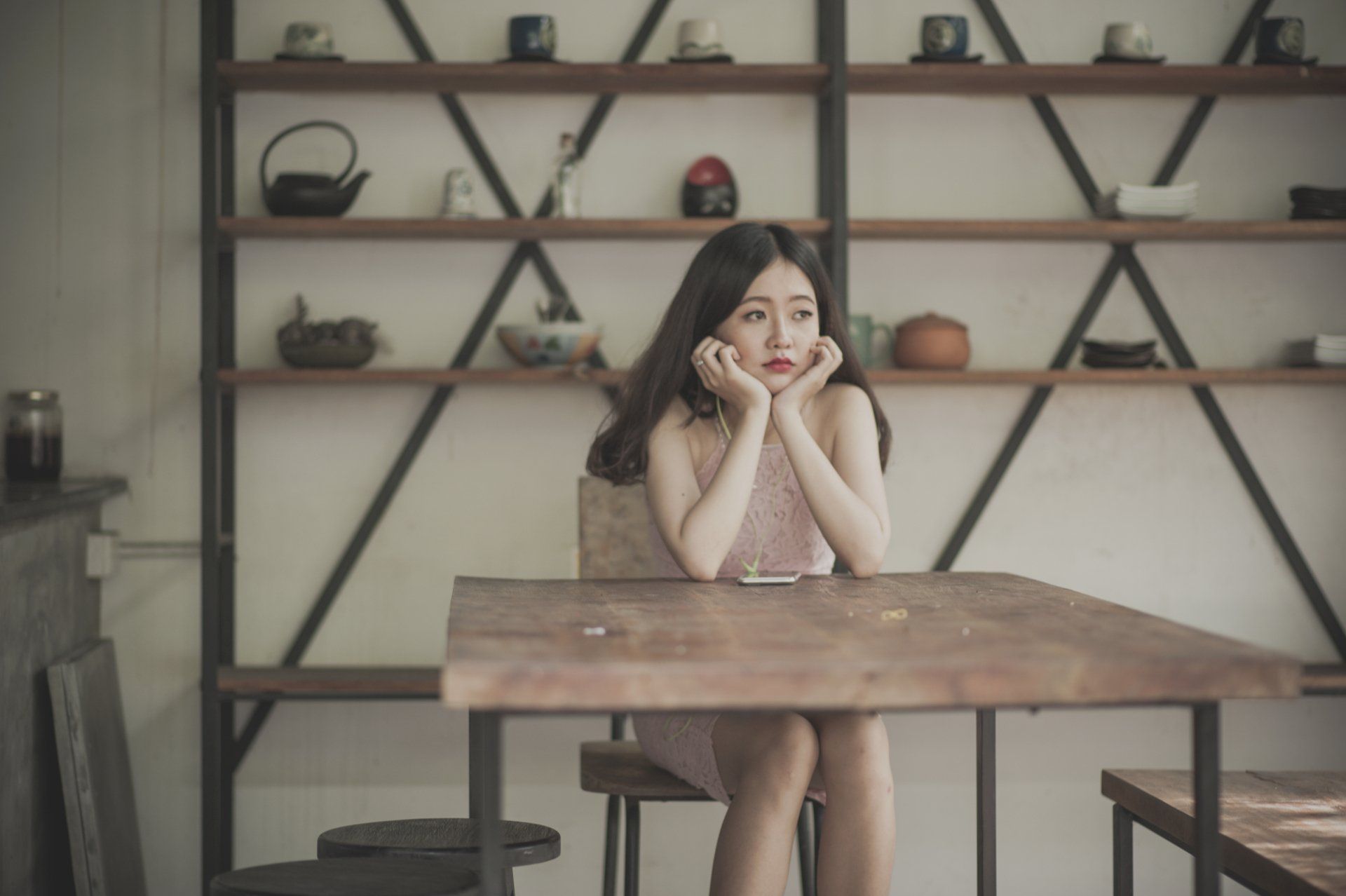 A woman is sitting at a table with her hands on her face.