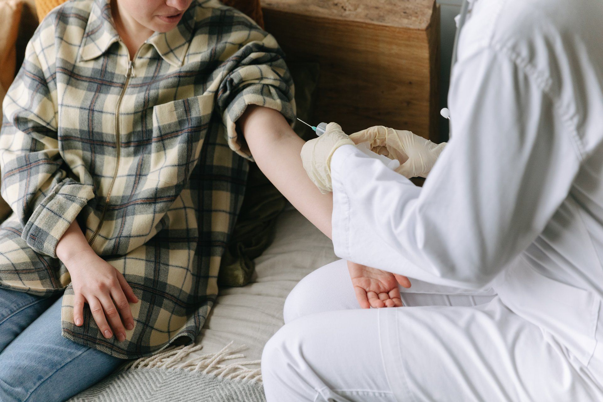 A woman is sitting on a bed getting an injection from a doctor.