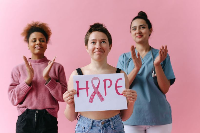three women are standing next to each other holding a sign that says hope .