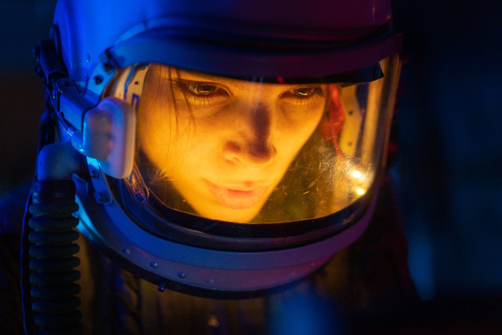 Astronaut in a dark environment, face illuminated through helmet.