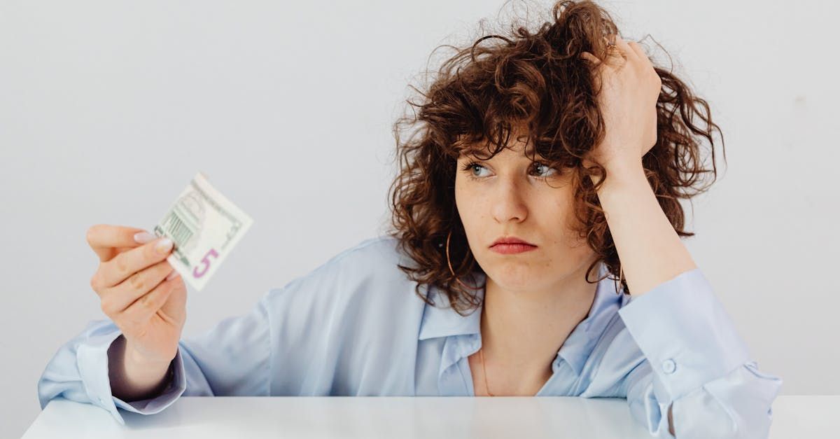 A woman is sitting at a table holding a piece of money .