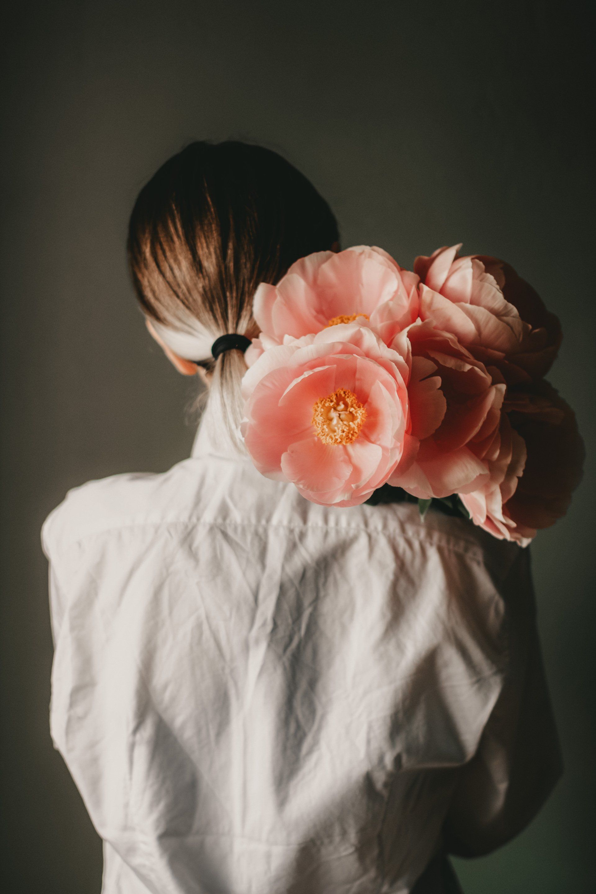 une femme tient un bouquet de fleurs roses dans sa queue de cheval